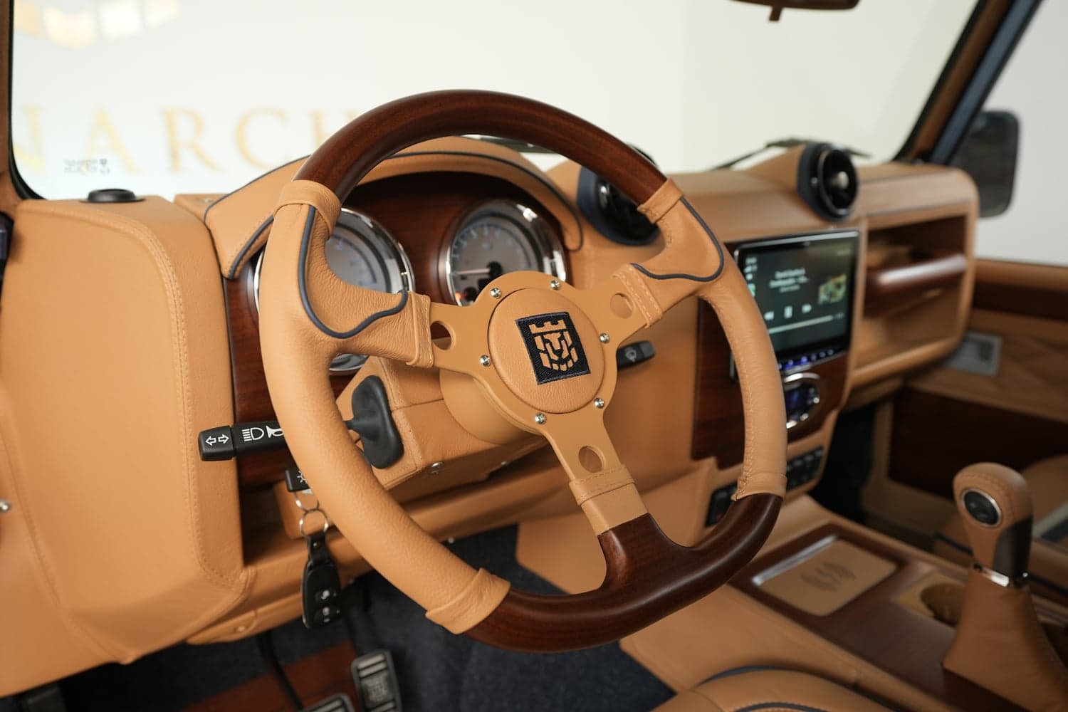 Close-up of a luxury steering wheel in a bespoke Land Rover Defender interior, featuring leather and wood accents