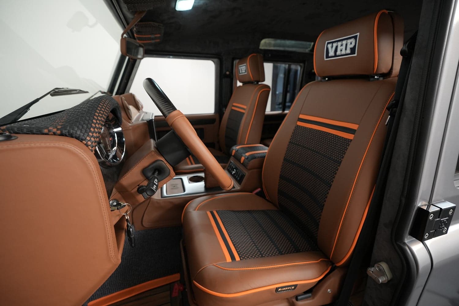Interior view of a custom Land Rover Defender with brown leather seats and orange accents