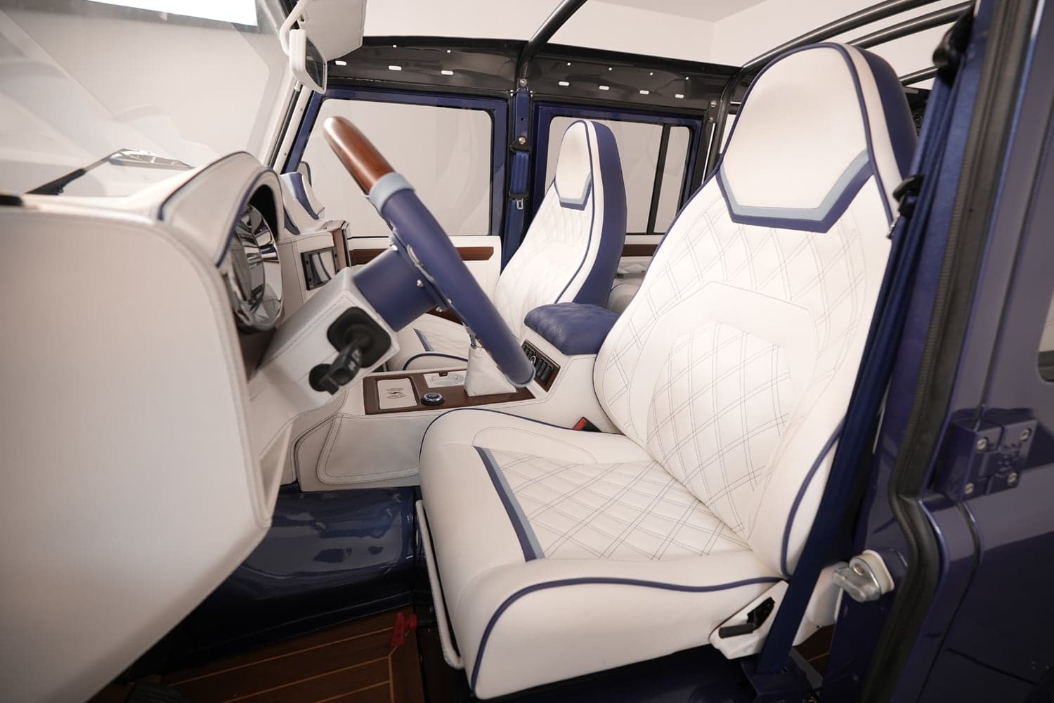 Luxury custom Land Rover Defender interior with white quilted leather seats and blue accents