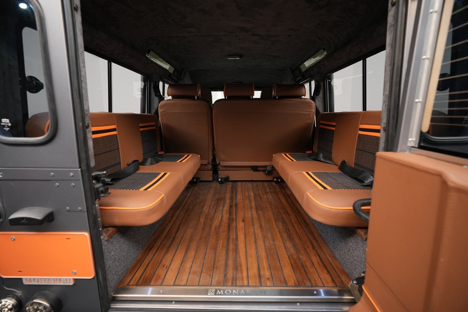 Interior of a custom Land Rover Defender with brown leather seats and wooden flooring