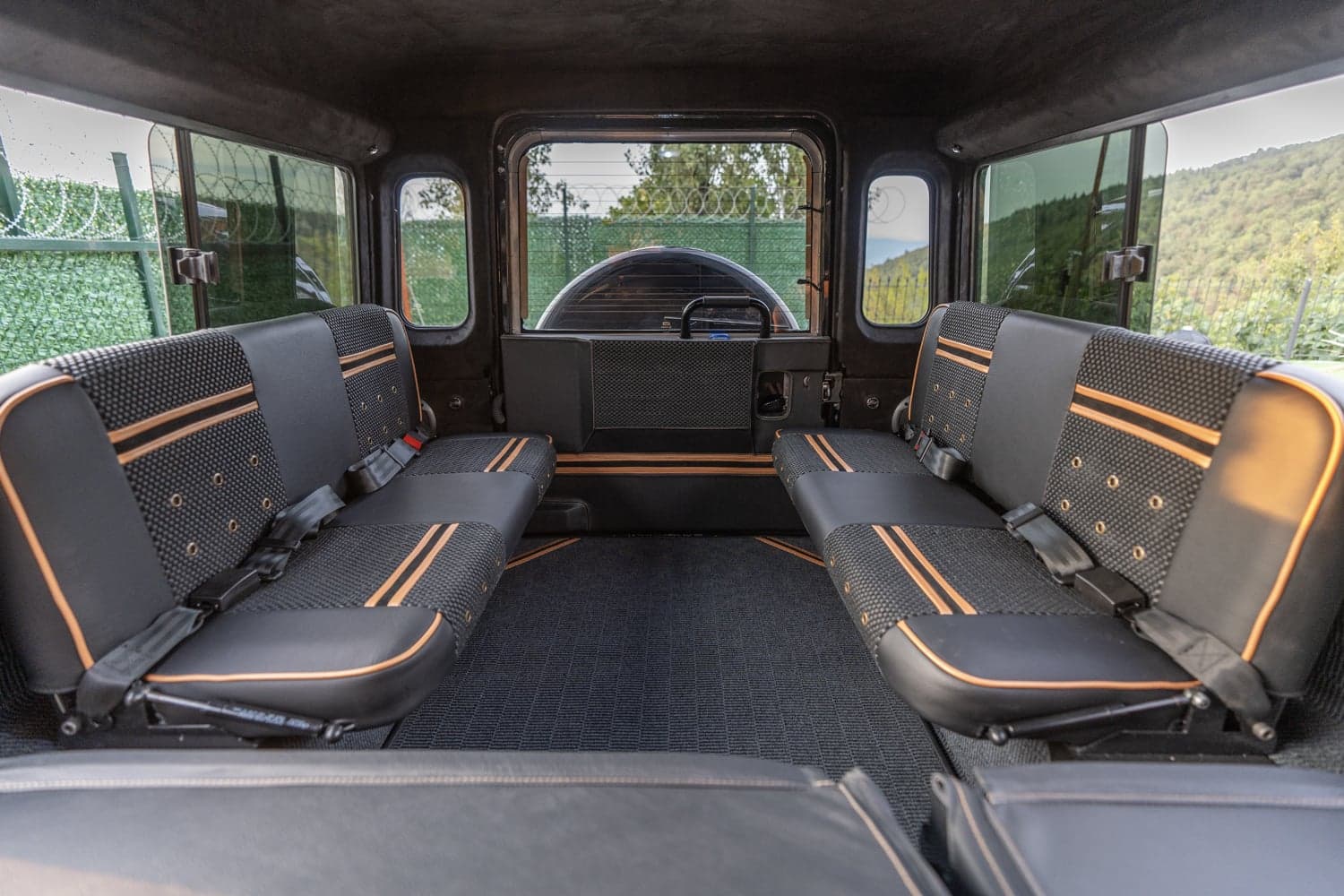 Interior view of a bespoke Land Rover Defender showing custom seating with black and orange accents