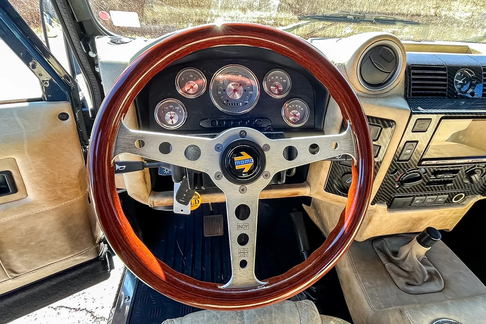 Interior Shot: Custom Steering Wheel Detailed view of a luxury custom Land Rover Defender interior featuring a wooden steering wheel and modern gauges