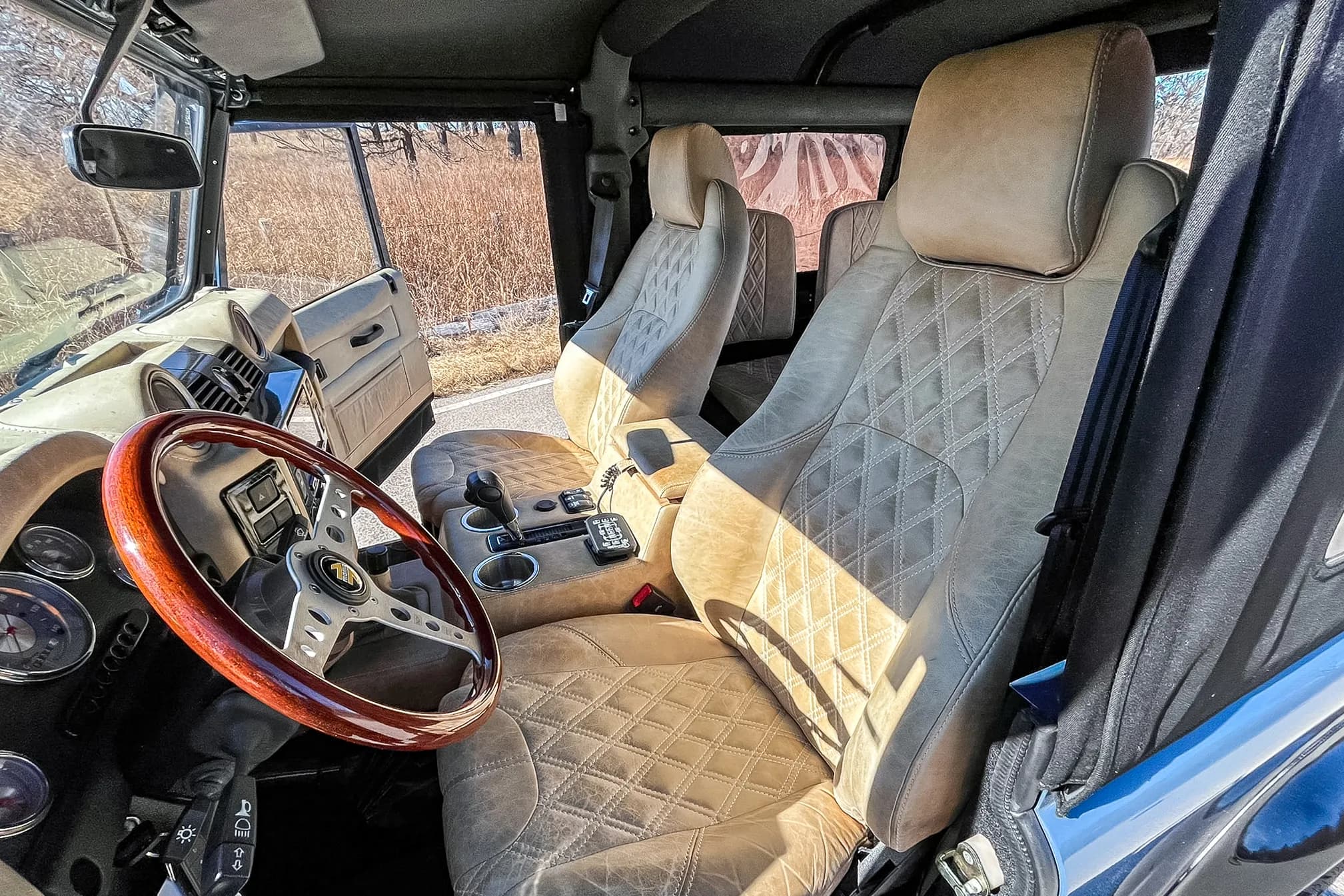 Interior Shot: Luxury Cabin Bespoke Land Rover Defender interior featuring tan quilted leather seats and a wooden steering wheel