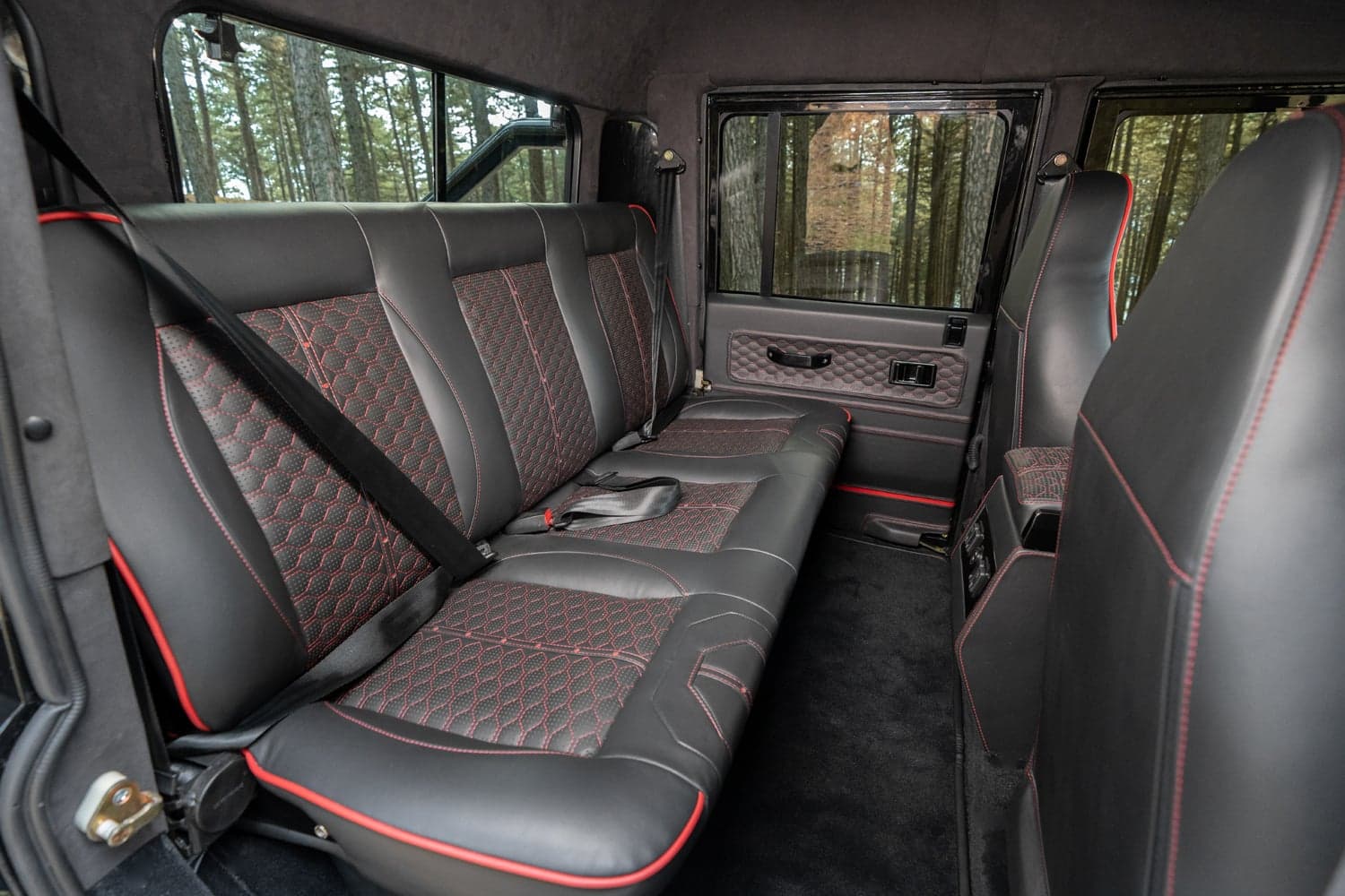 Interior Shot: Luxury Rear Seating Bespoke Land Rover Defender rear interior featuring premium leather seats with red stitching