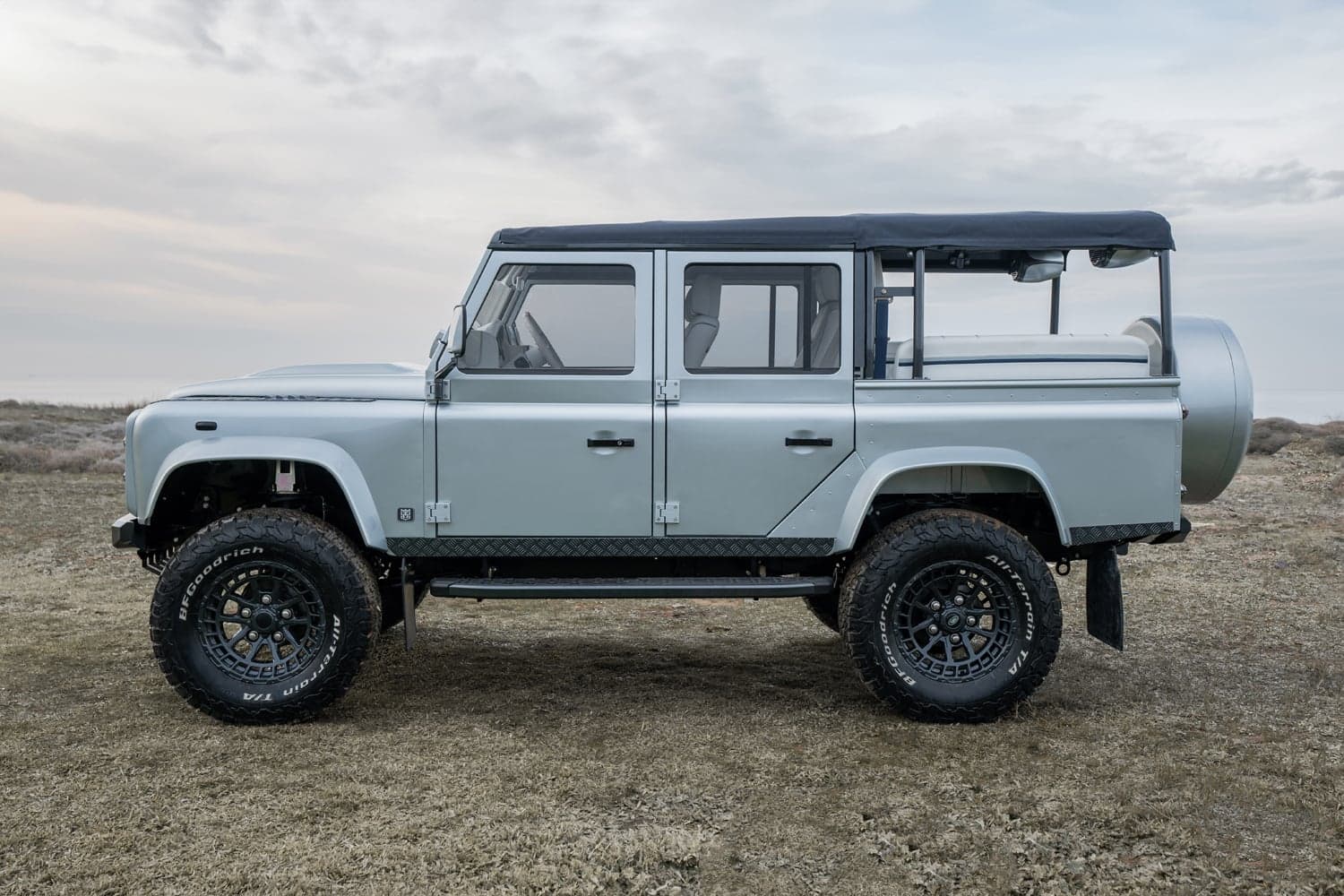 Side View: Bespoke Land Rover Defender Custom Land Rover Defender in a light silver finish with off-road tires and a soft top