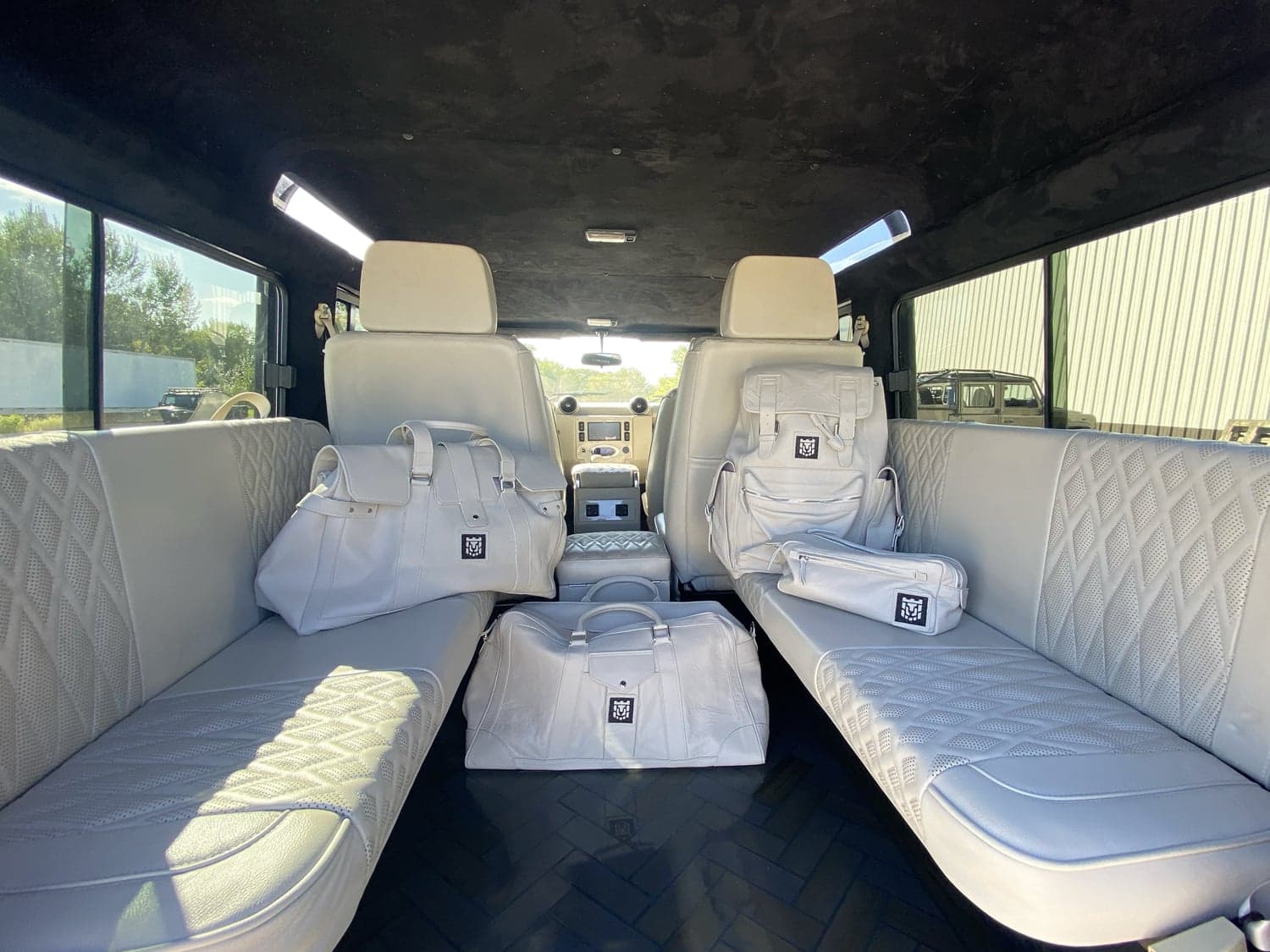 Interior Shot: Luxury Cabin Interior of a custom Land Rover Defender featuring premium white leather seating and designer bags