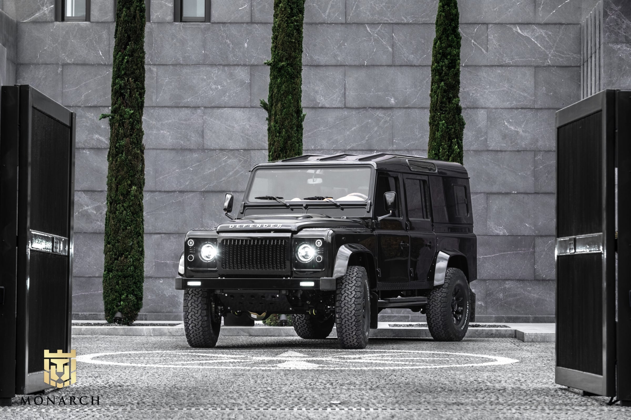 Front View: Bespoke Land Rover Defender Custom black Land Rover Defender parked in a modern setting