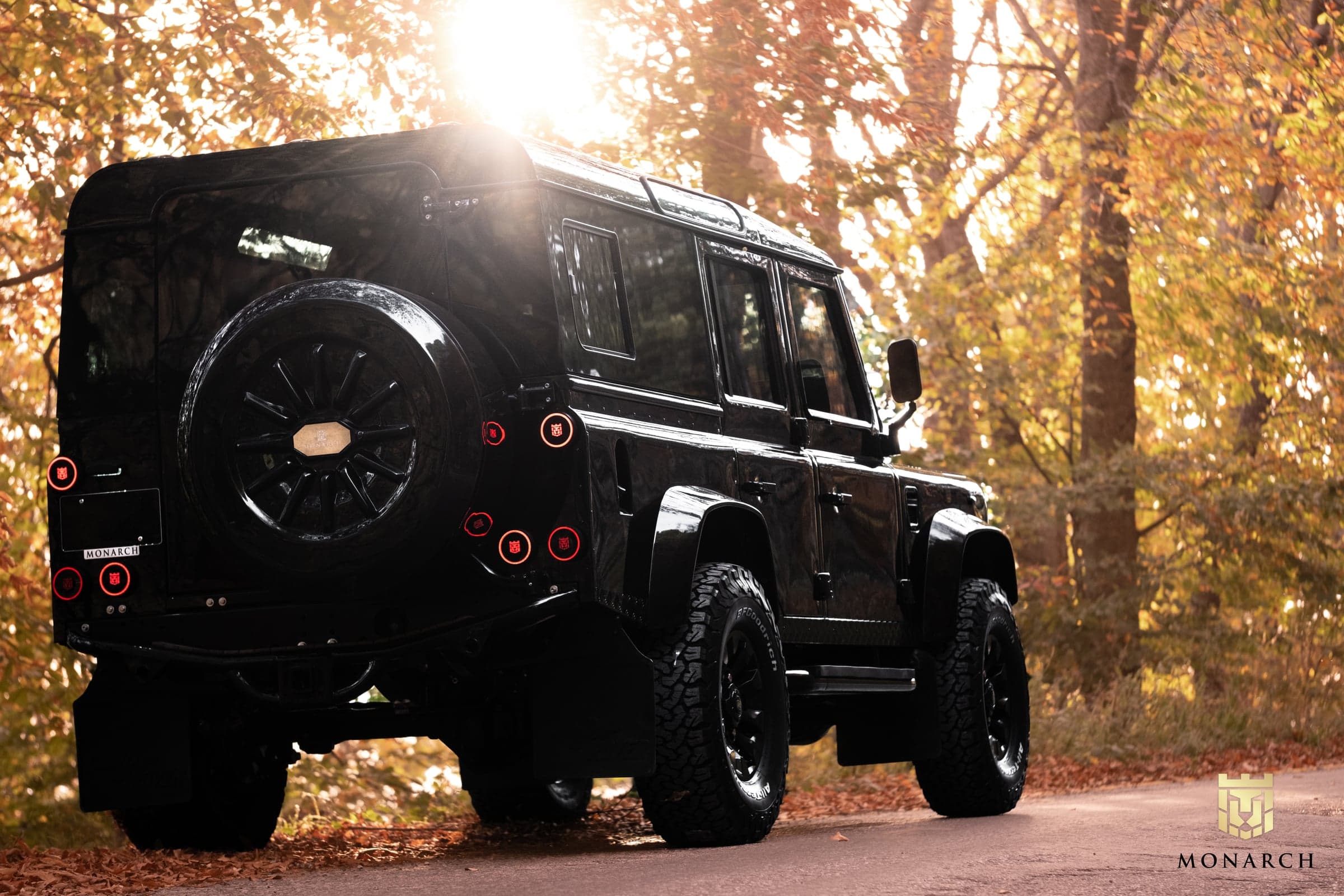 Rear View: Custom Black Defender Custom Land Rover Defender in black parked on a scenic road