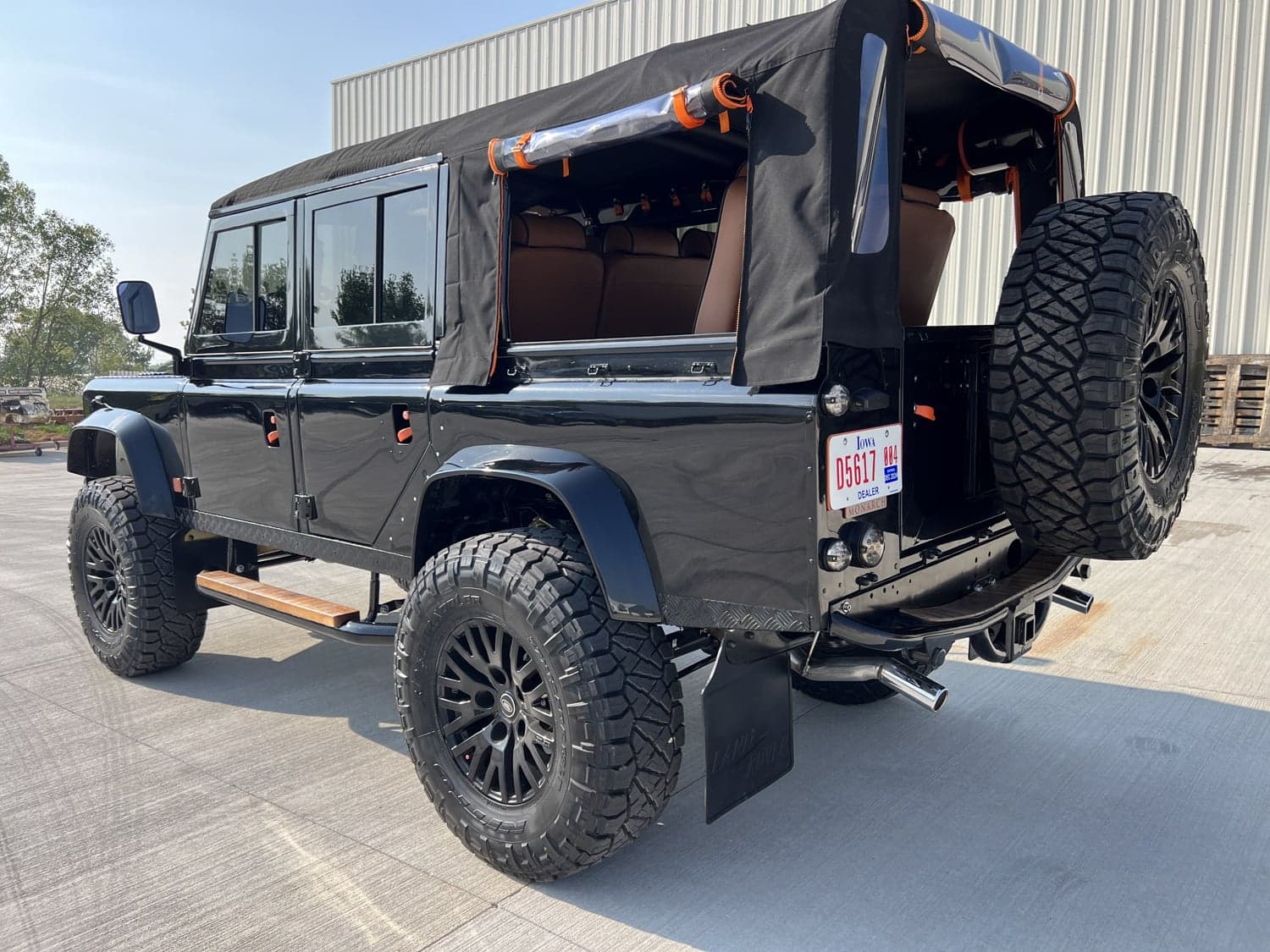 Rear View: Custom Land Rover Defender Black custom Land Rover Defender with a soft top and oversized tires
