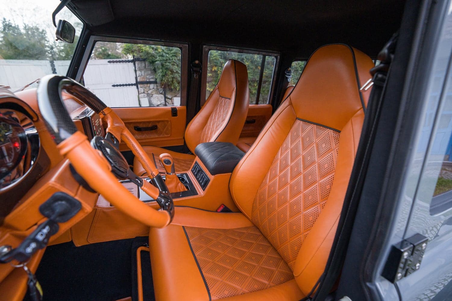 Interior Shot: Luxurious Cabin Design Interior view of a custom Land Rover Defender featuring orange leather seats and a stylish dashboard