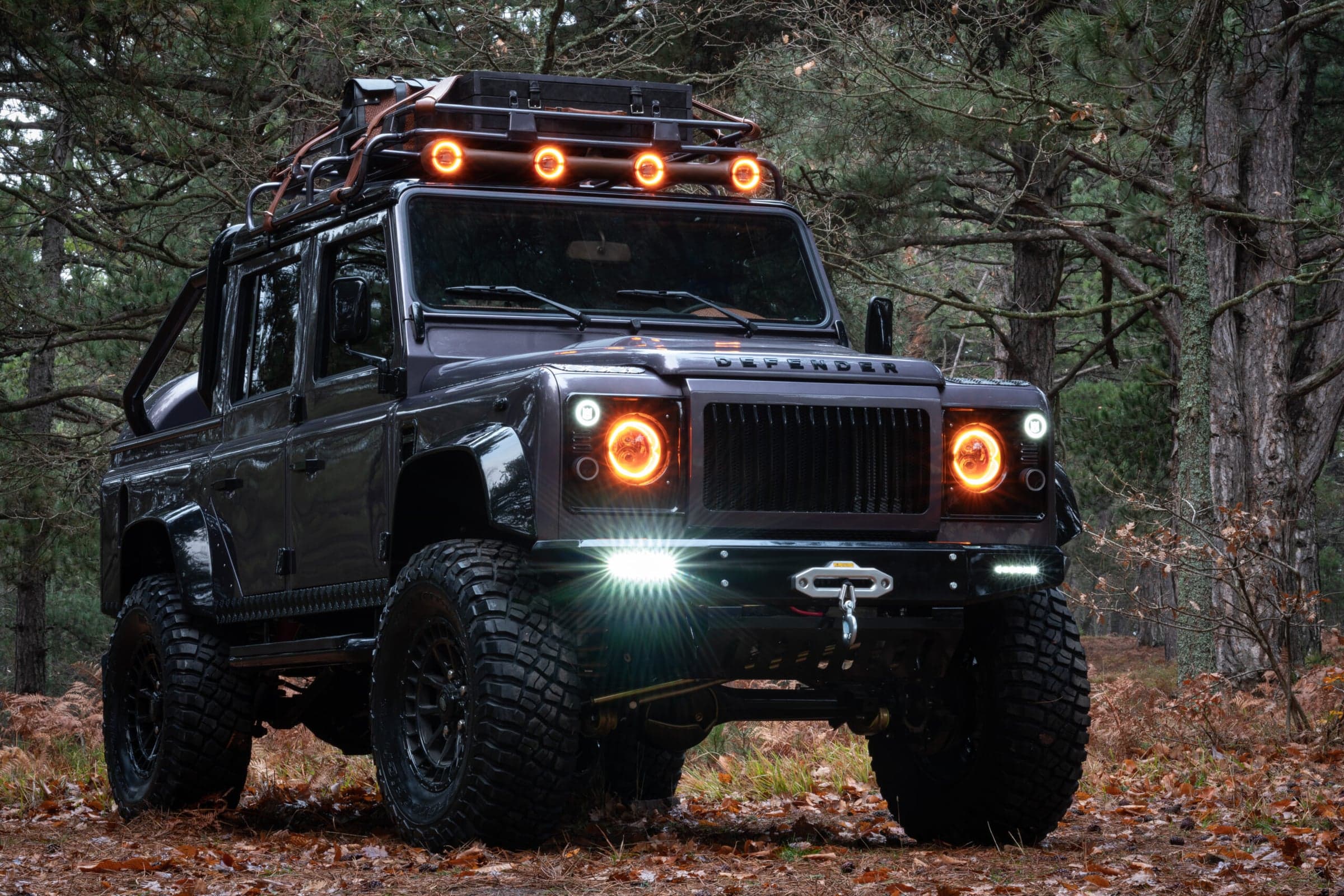 Front View: Custom Land Rover Defender Front view of a bespoke Land Rover Defender with custom modifications in a forest setting