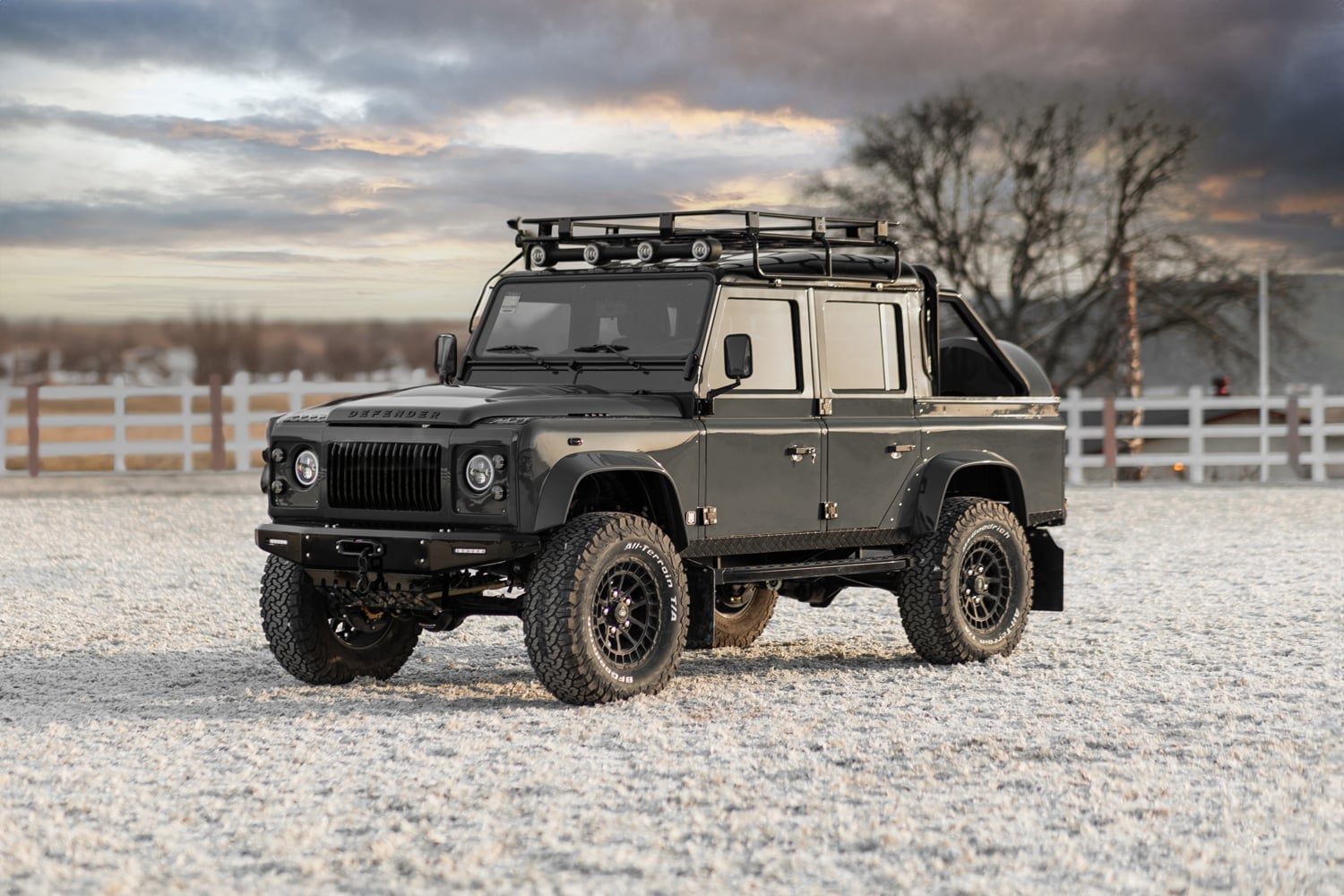 Front View: Custom Land Rover Defender Front view of a bespoke black Land Rover Defender with a roof rack and off-road tires