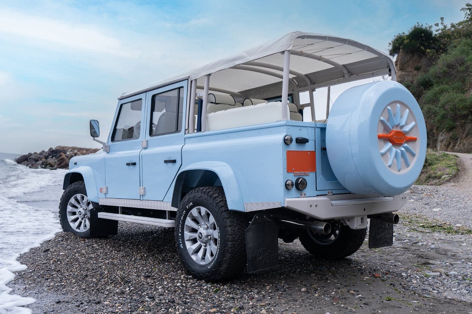 Studio Photo: Bespoke Land Rover Defender Custom light blue Land Rover Defender parked on a beach with white interior and spare tire cover