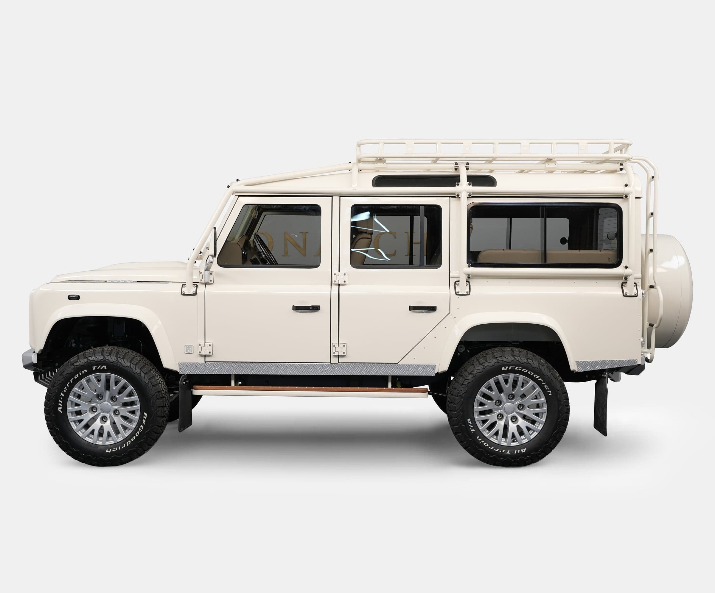 Side View: Custom Land Rover Defender Side view of a bespoke Land Rover Defender in cream color with a roof rack and luxury wheels