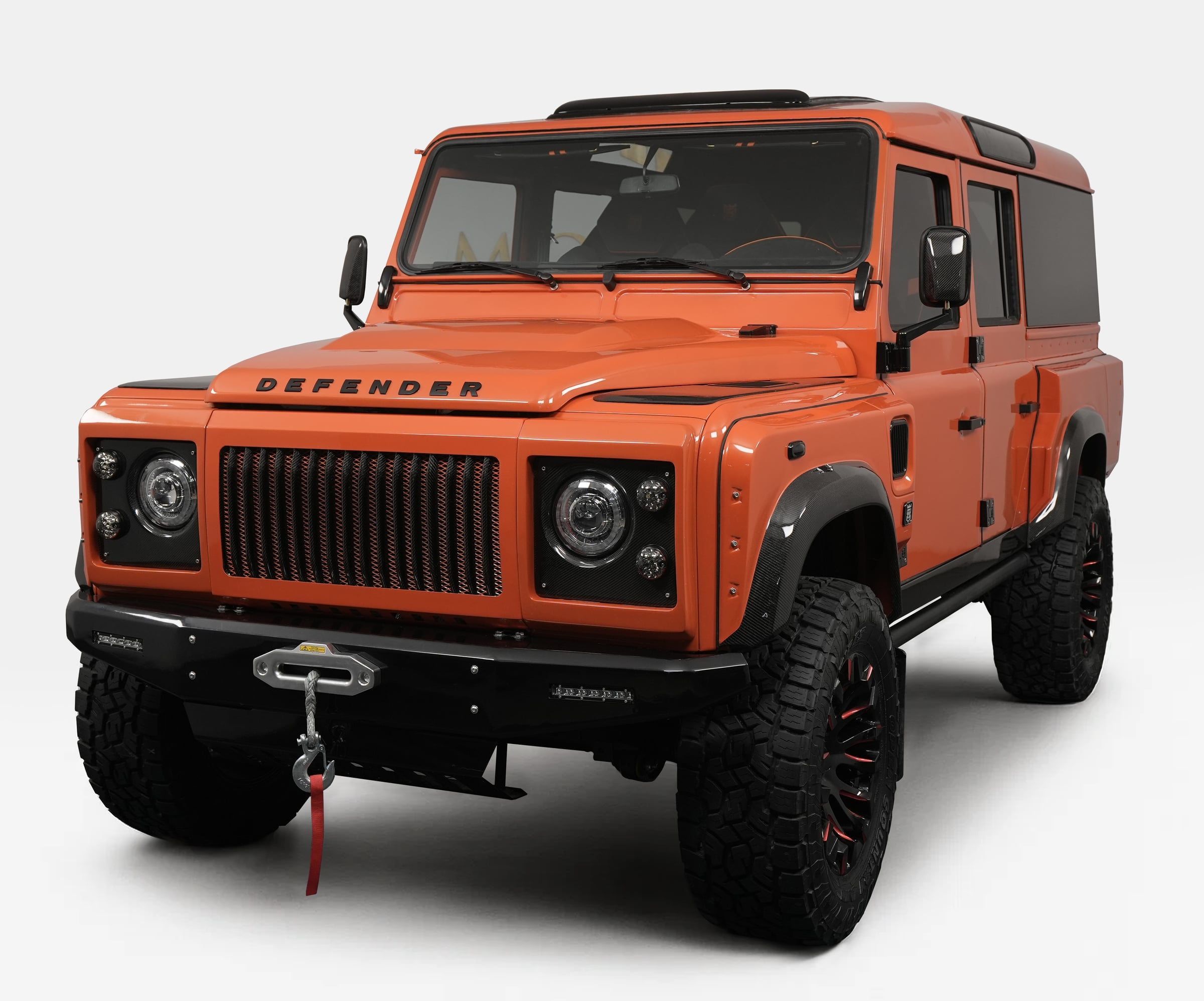 Front View: Custom Orange Defender Custom Land Rover Defender in vibrant orange color with rugged tires and off-road features