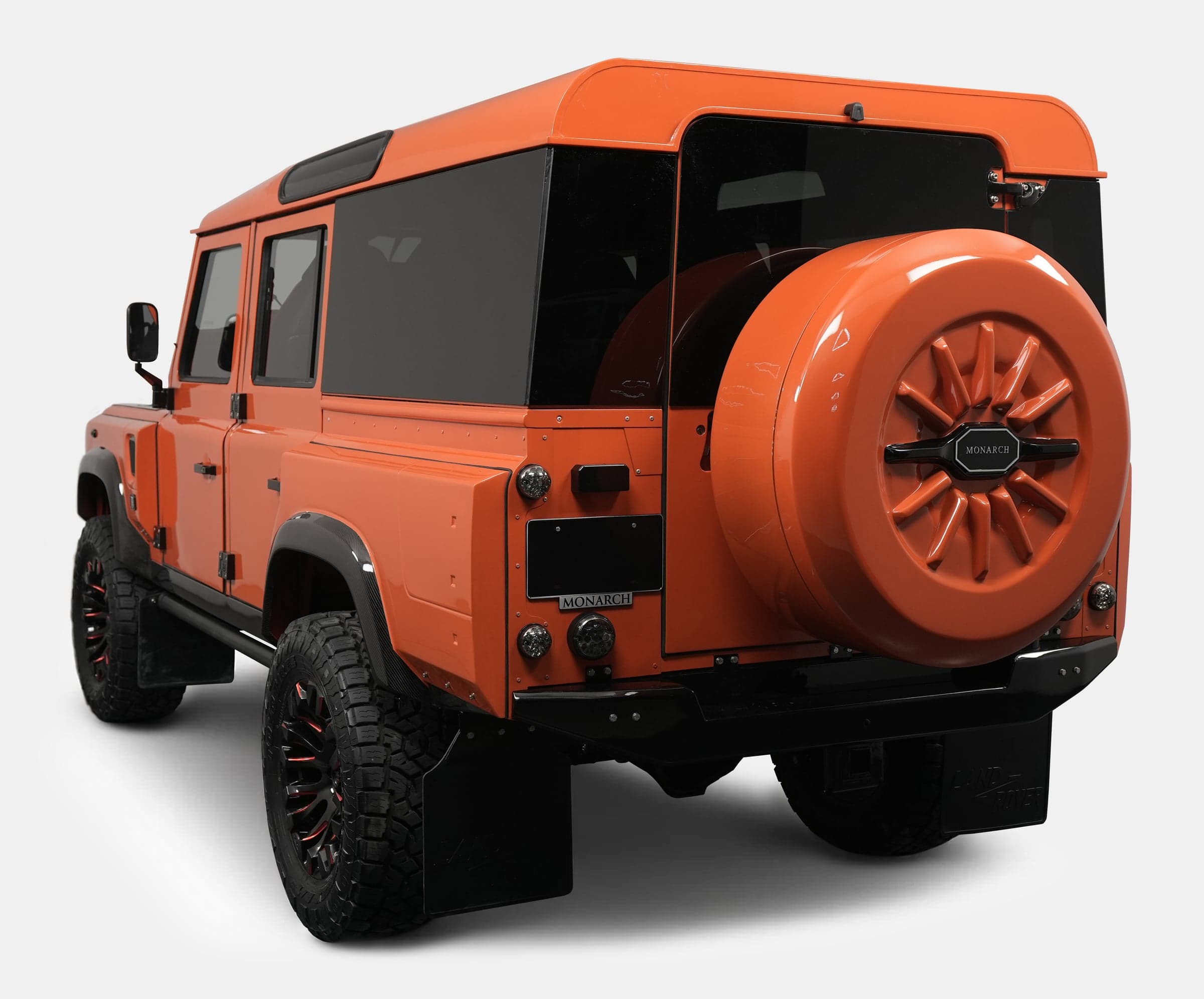 Rear View: Custom Orange Defender Rear view of a custom orange Land Rover Defender with black accents and unique wheel design