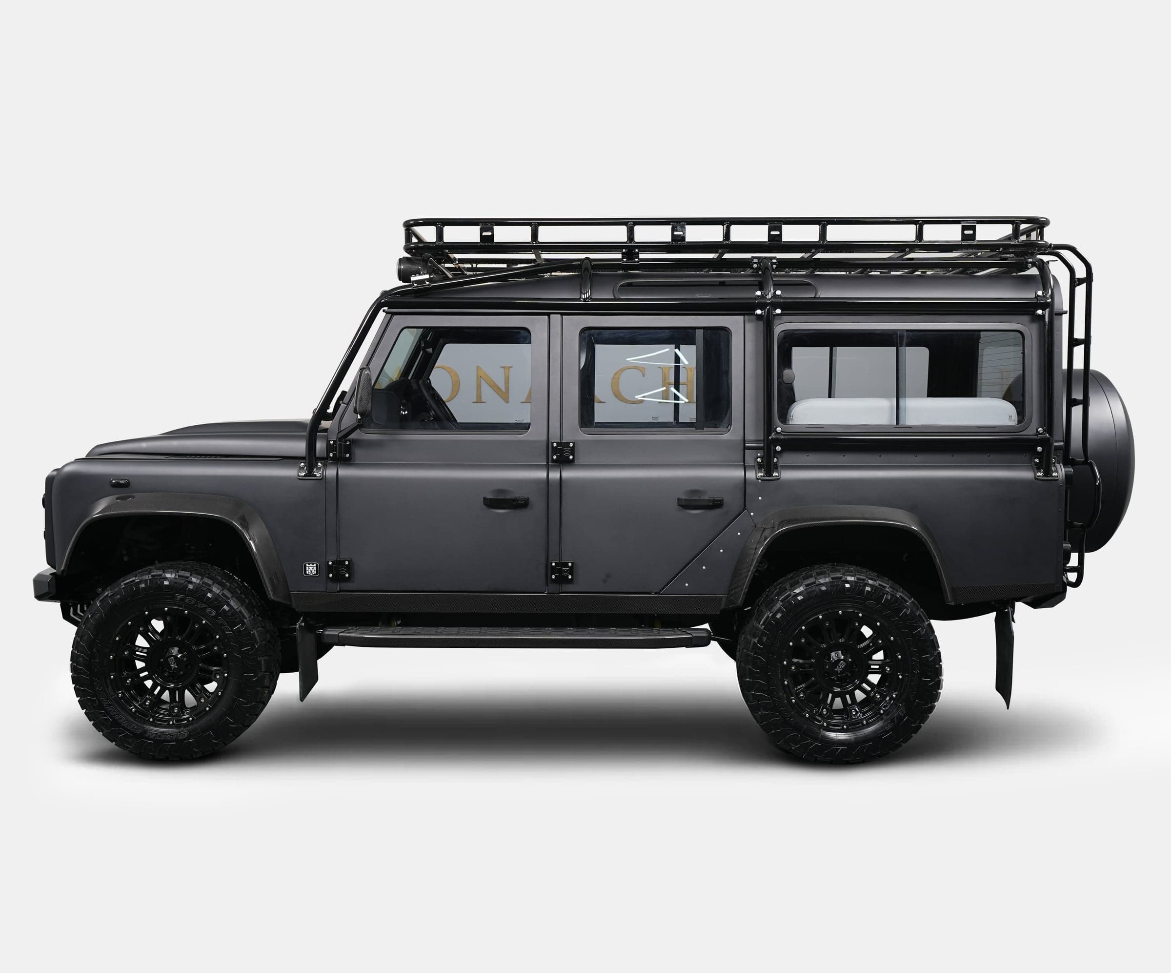 Side View: Custom Land Rover Defender Side view of a bespoke Land Rover Defender with a matte black finish and rugged off-road tires