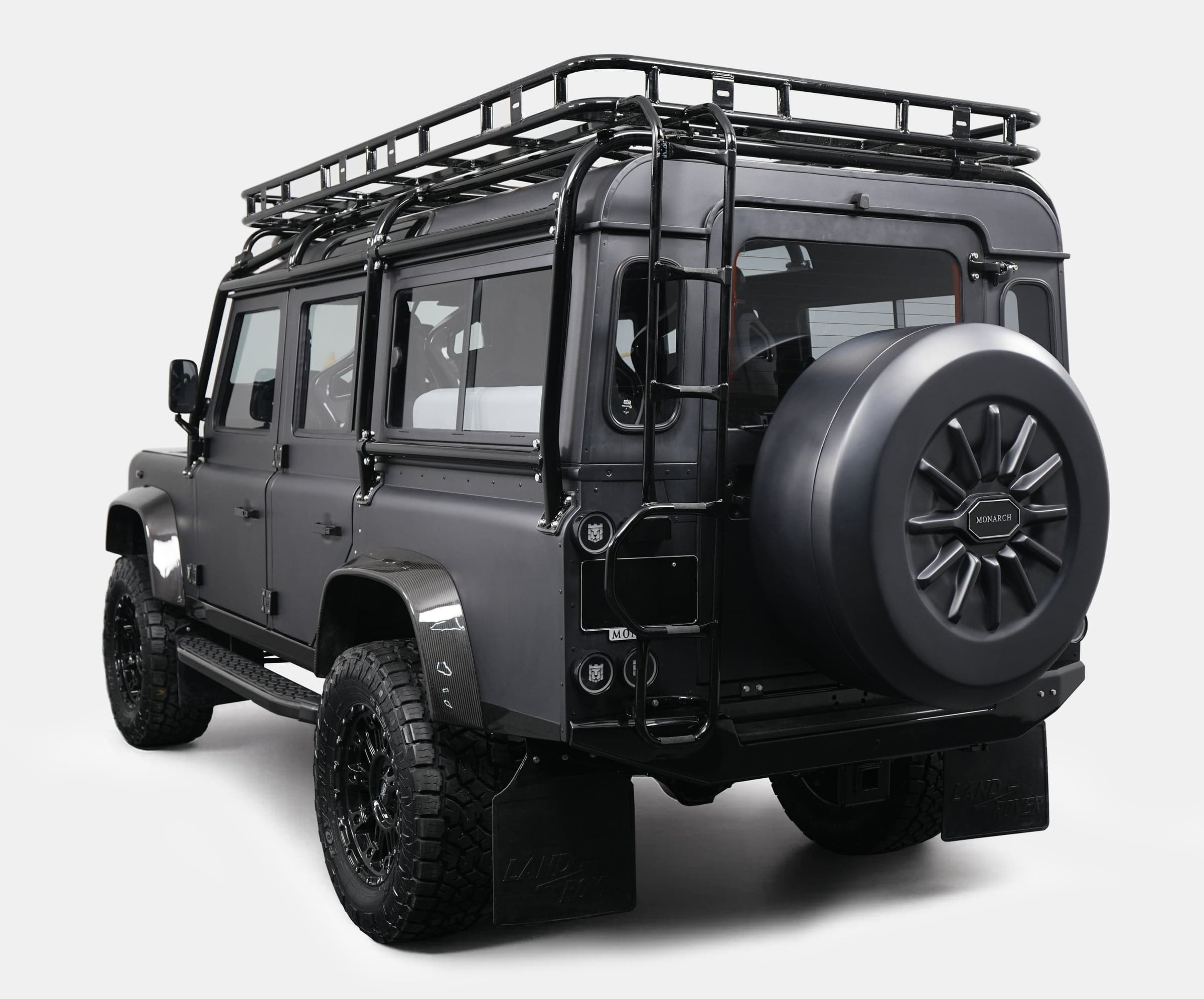 Rear View: Bespoke Land Rover Defender Rear view of a custom Land Rover Defender with a black matte finish and roof rack