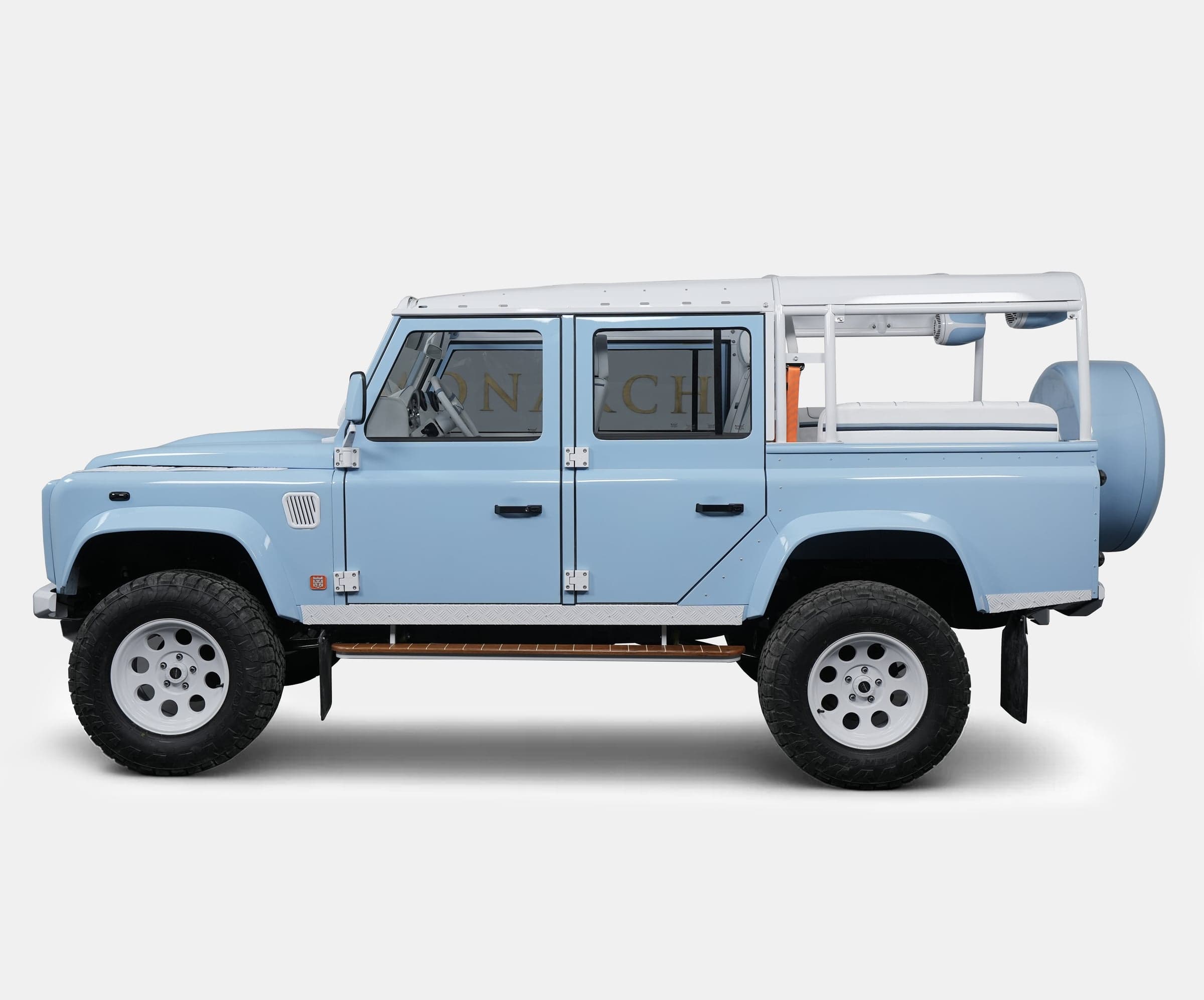 Side View: Custom Land Rover Defender Custom Land Rover Defender in light blue with a white roll cage and off-road tires