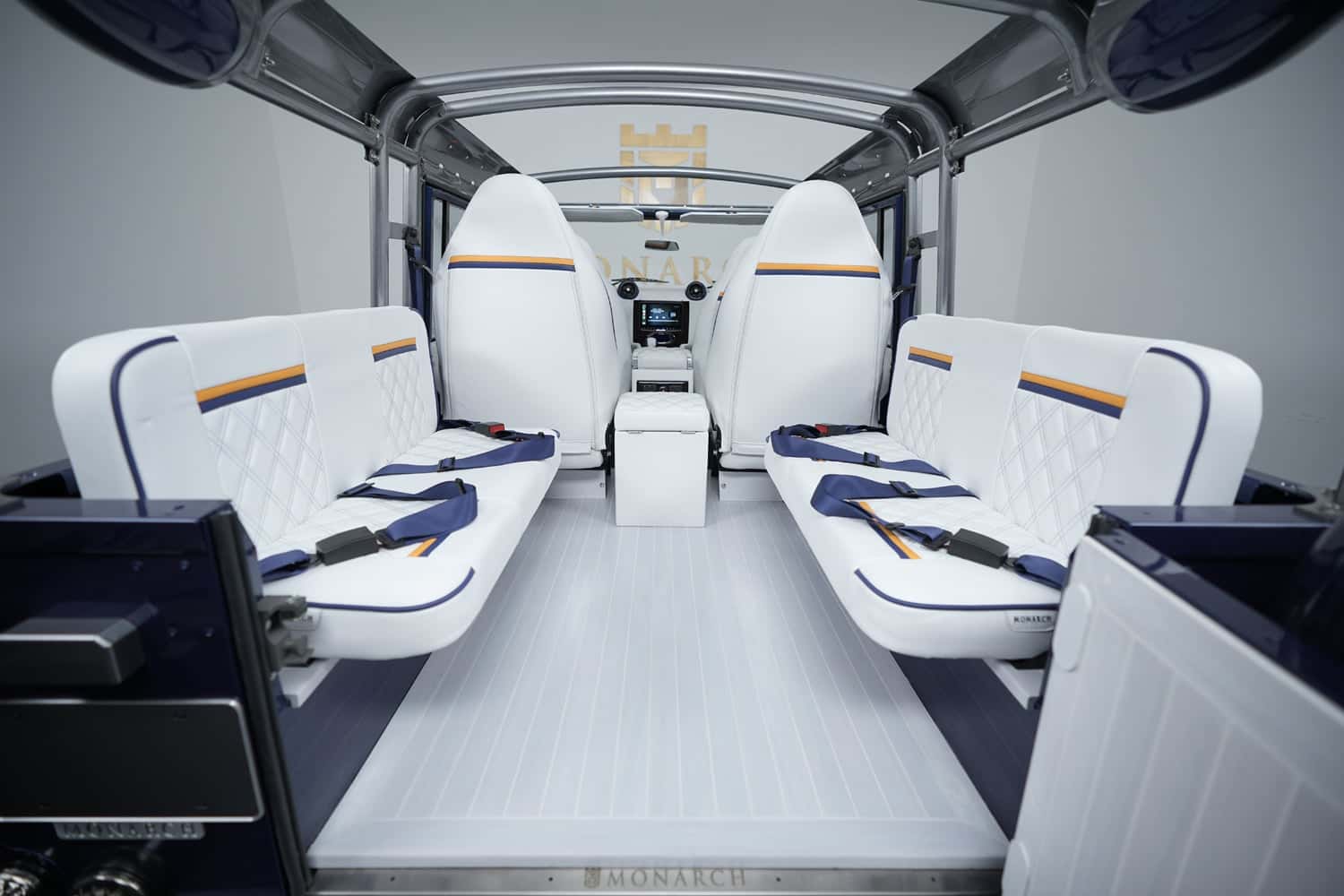 Interior of a custom Land Rover Defender featuring white leather seats with diamond stitching and blue accents