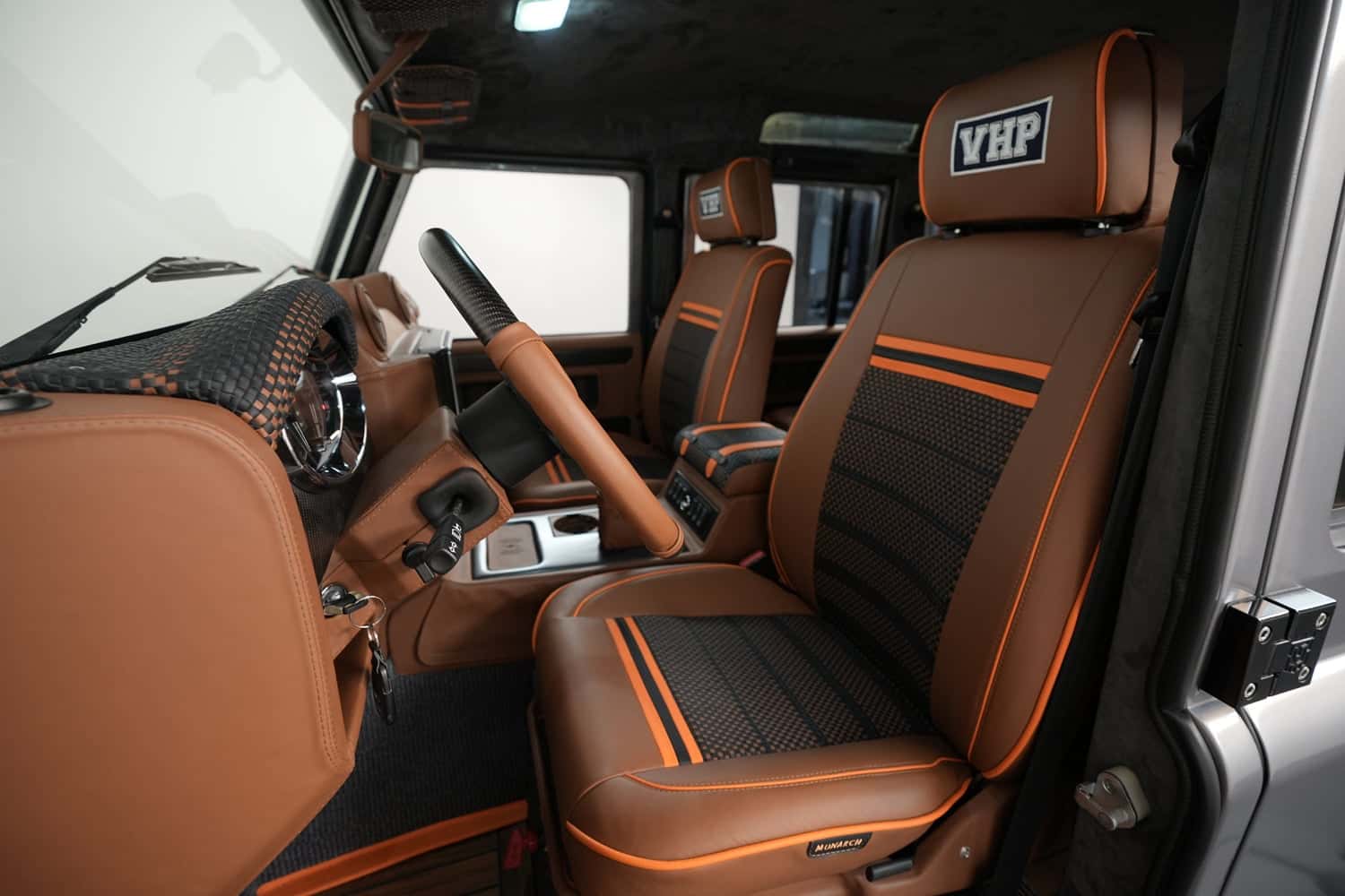 Interior view of a custom Land Rover Defender with brown leather seats and orange accents