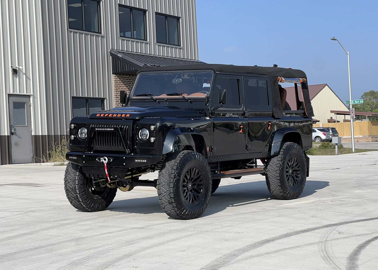 Custom black Land Rover Defender with a soft top and rugged tires