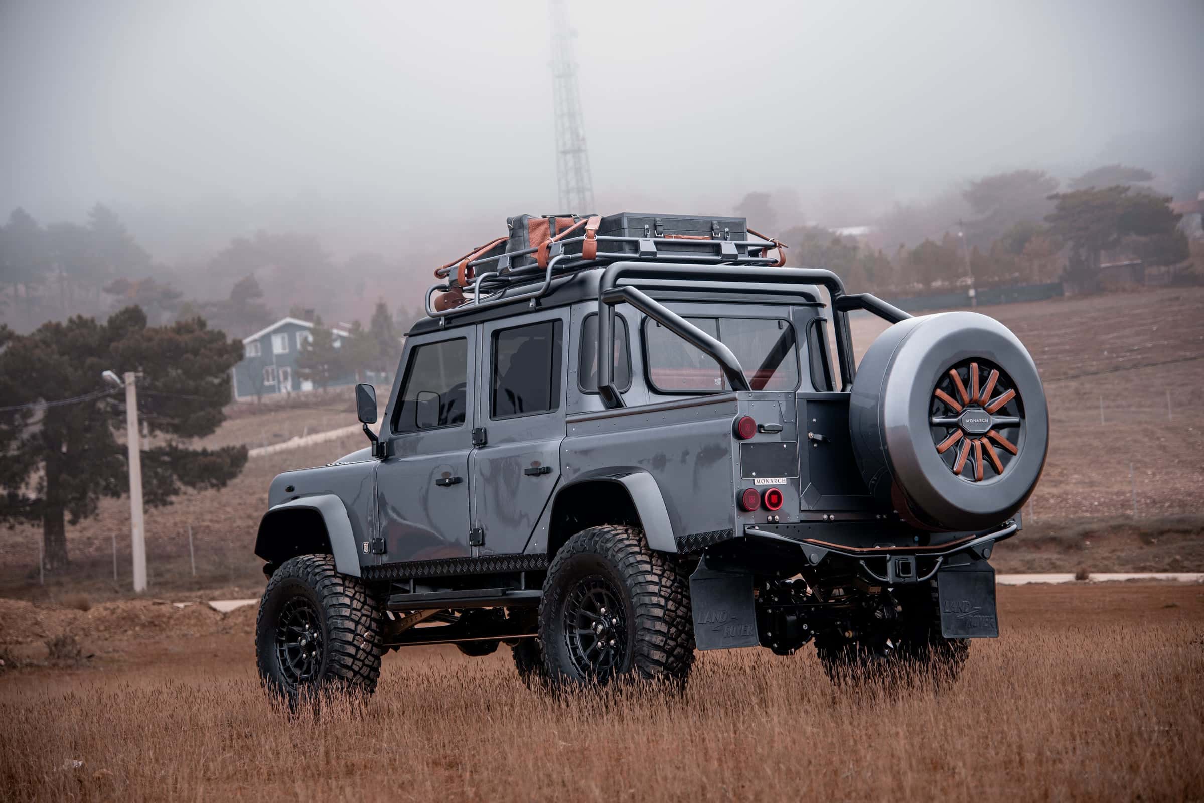 Custom Land Rover Defender in grey with off-road tires and roof rack