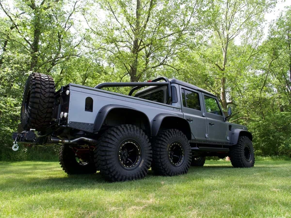 Custom Land Rover Defender in grey with large off-road tires parked in a grassy area