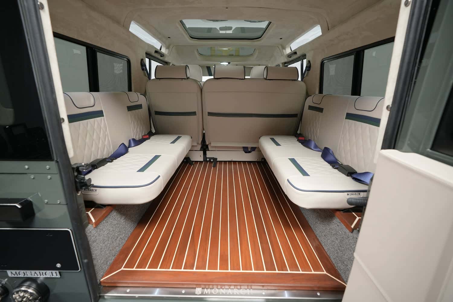 Interior view of a custom Land Rover Defender featuring luxurious seating and wooden flooring