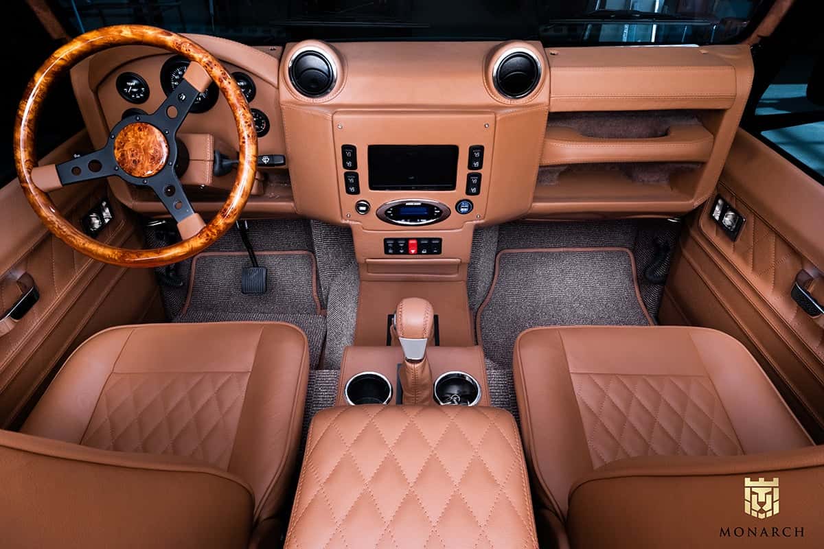 Luxurious interior of a custom Land Rover Defender with premium tan leather seats and wooden steering wheel