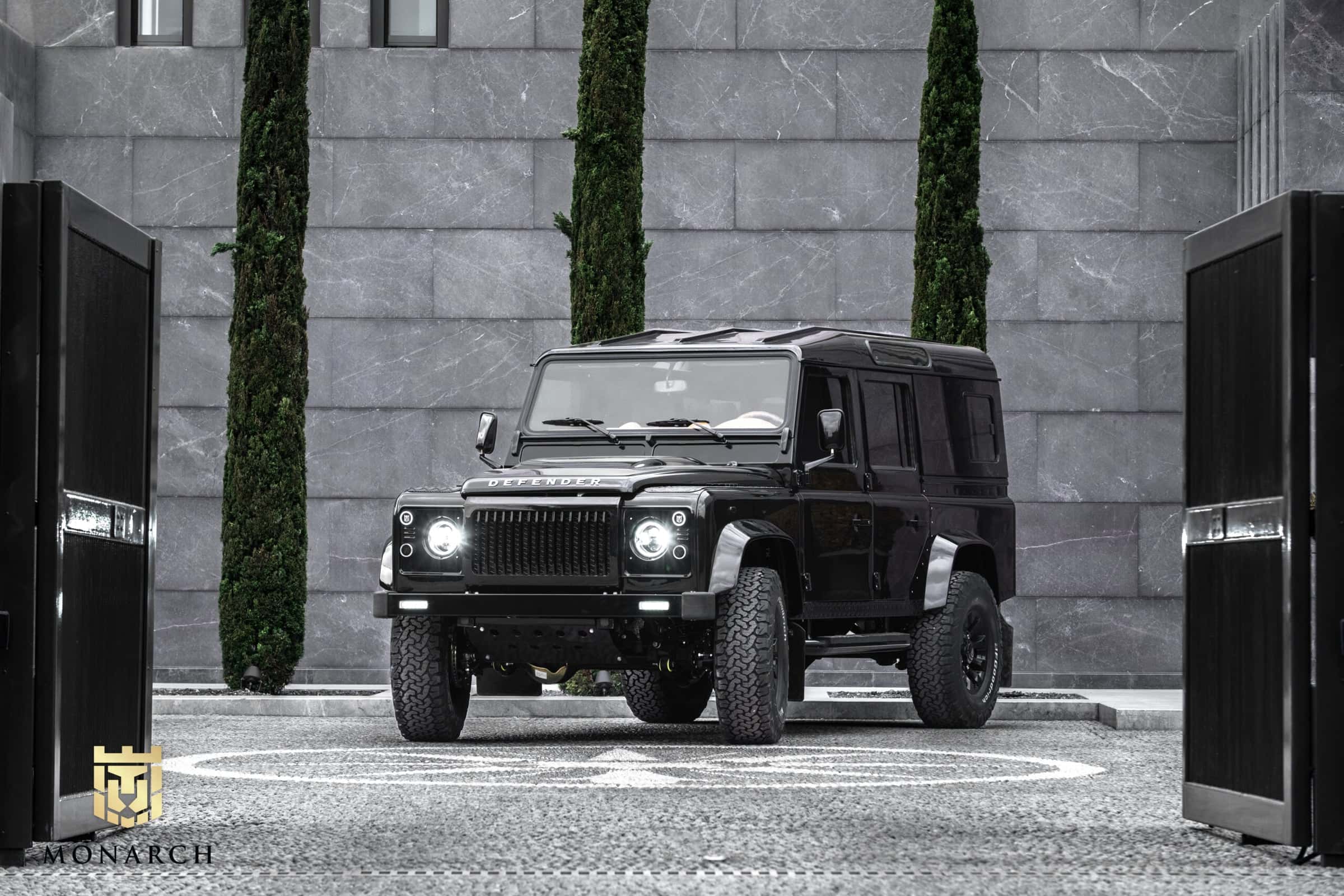 Custom black Land Rover Defender parked in a modern setting