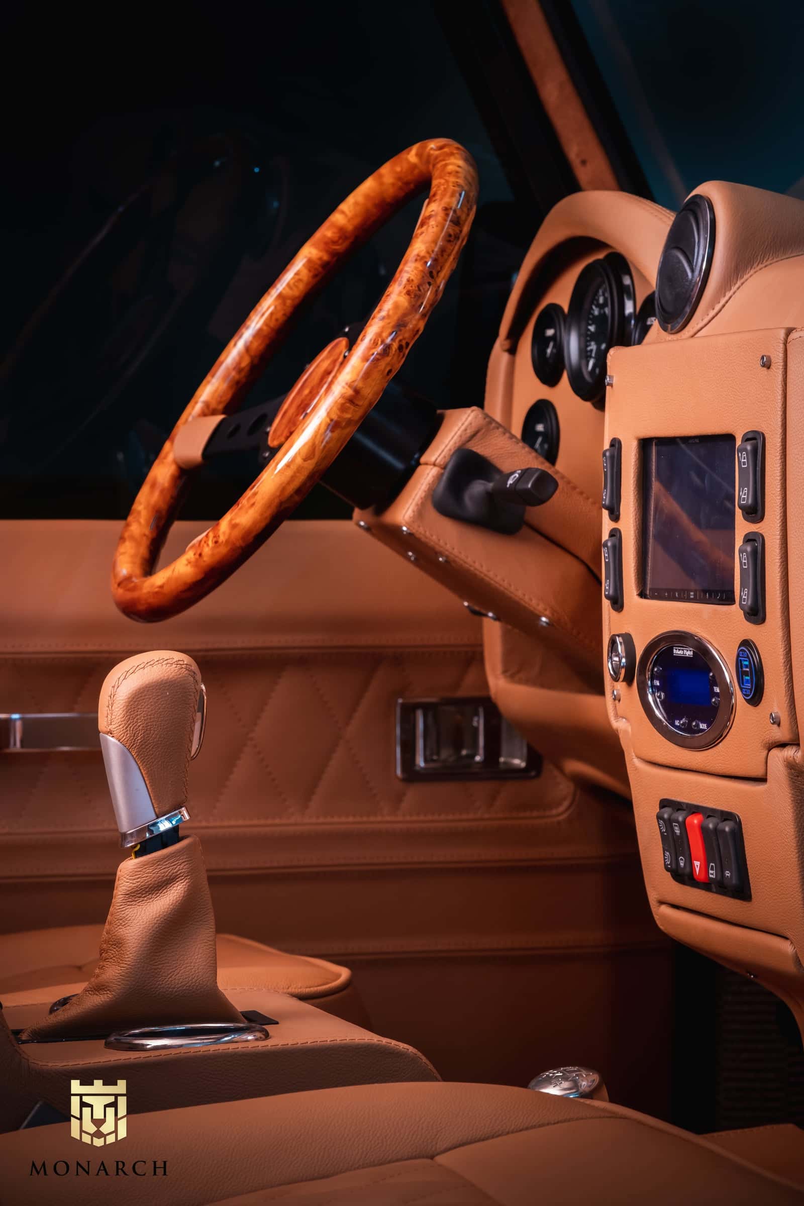 Close-up of a luxury Land Rover Defender interior featuring a wooden steering wheel, leather seats, and modern controls