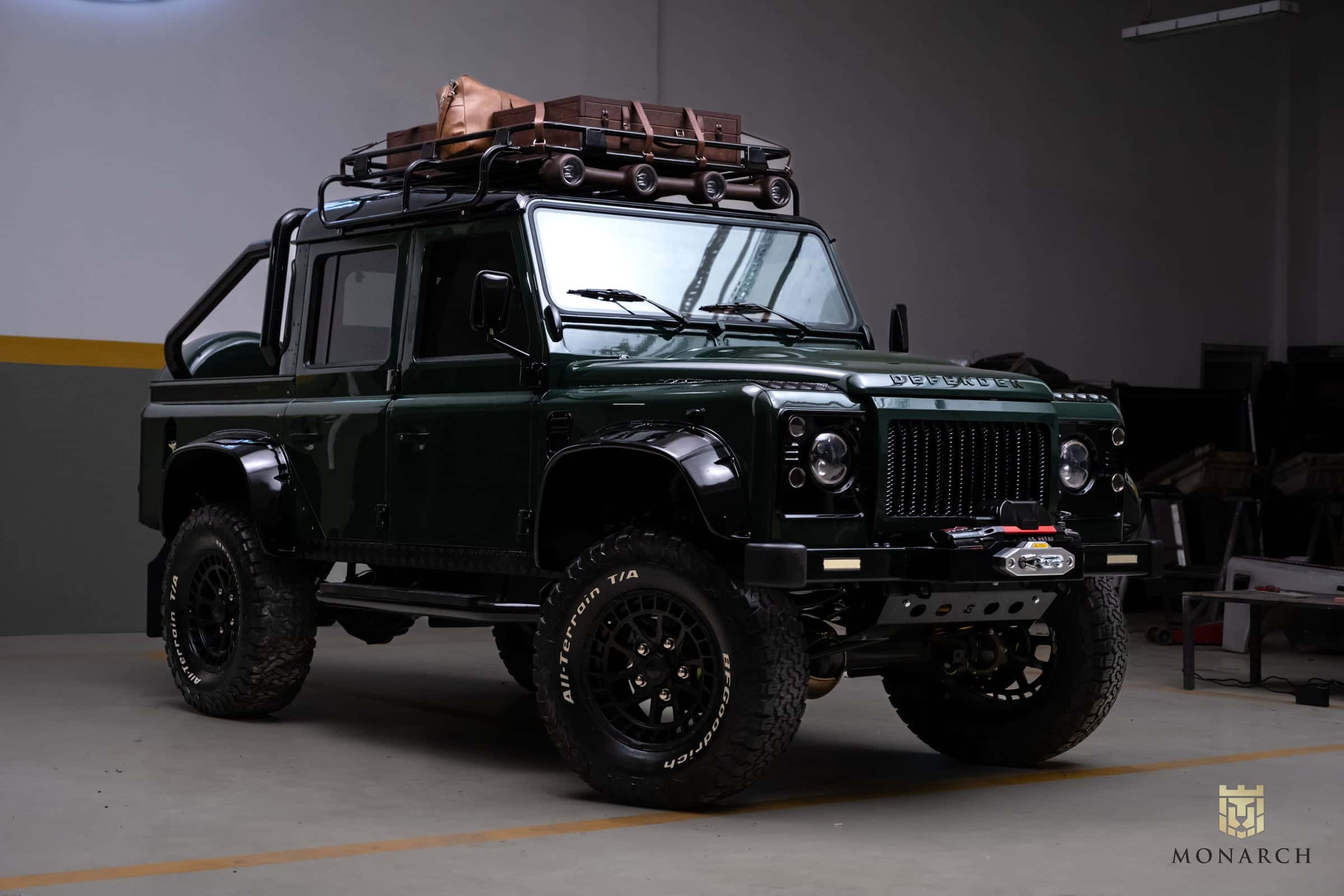 Bespoke green Land Rover Defender with roof rack and luggage
