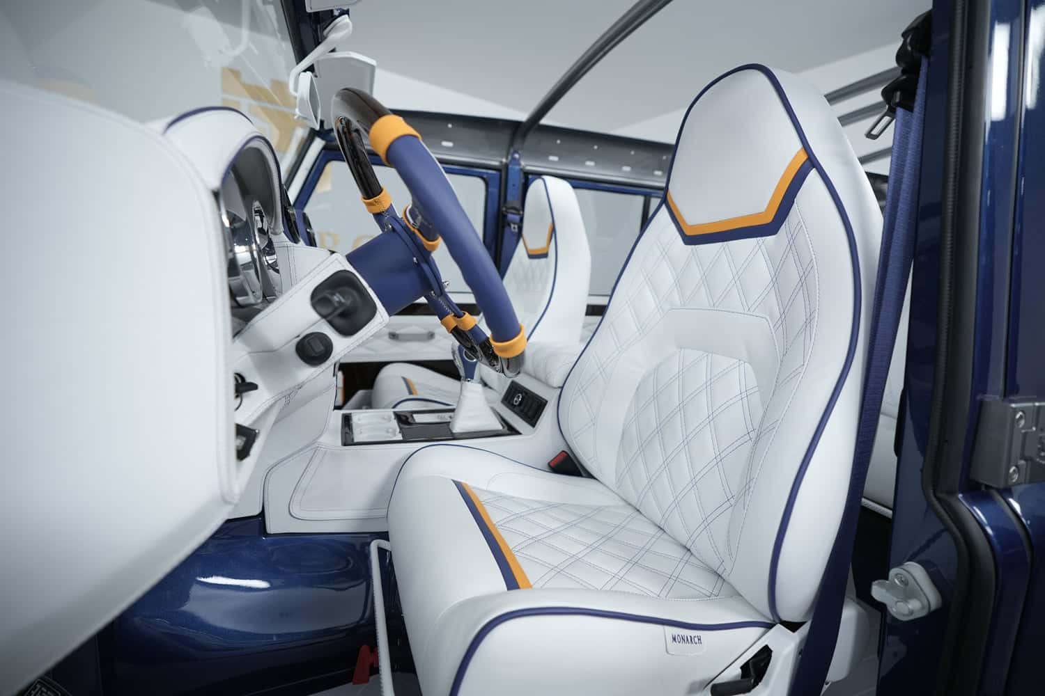 Custom Land Rover Defender interior featuring white leather seats with orange and blue accents