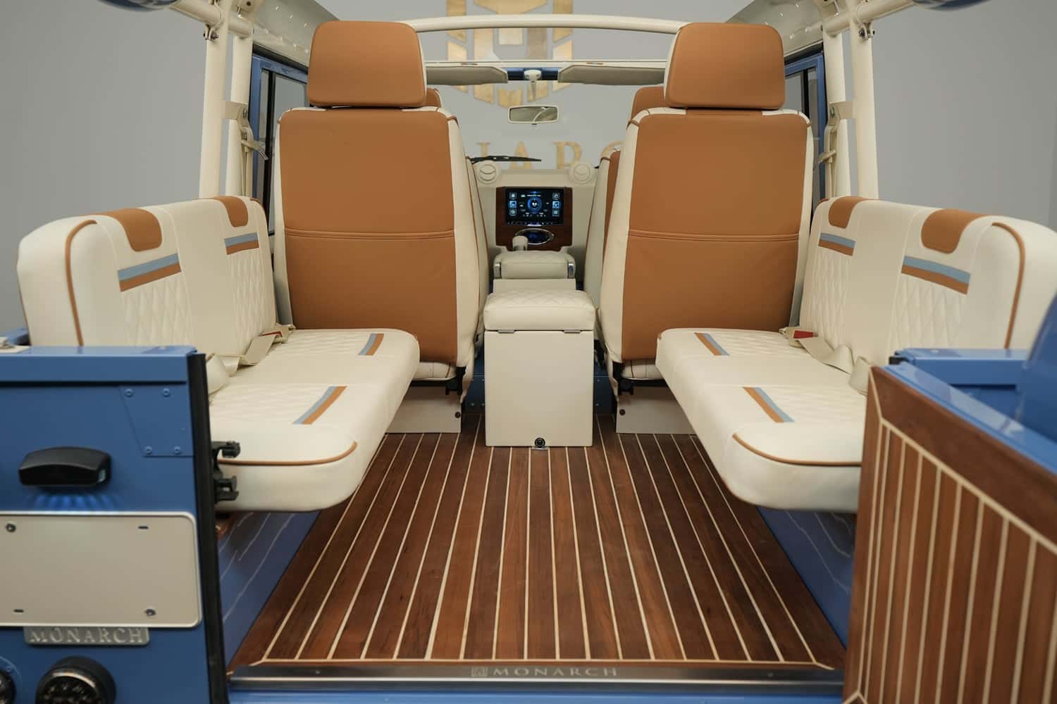 Interior view of a luxury custom Land Rover Defender with tan and cream seating and wooden flooring
