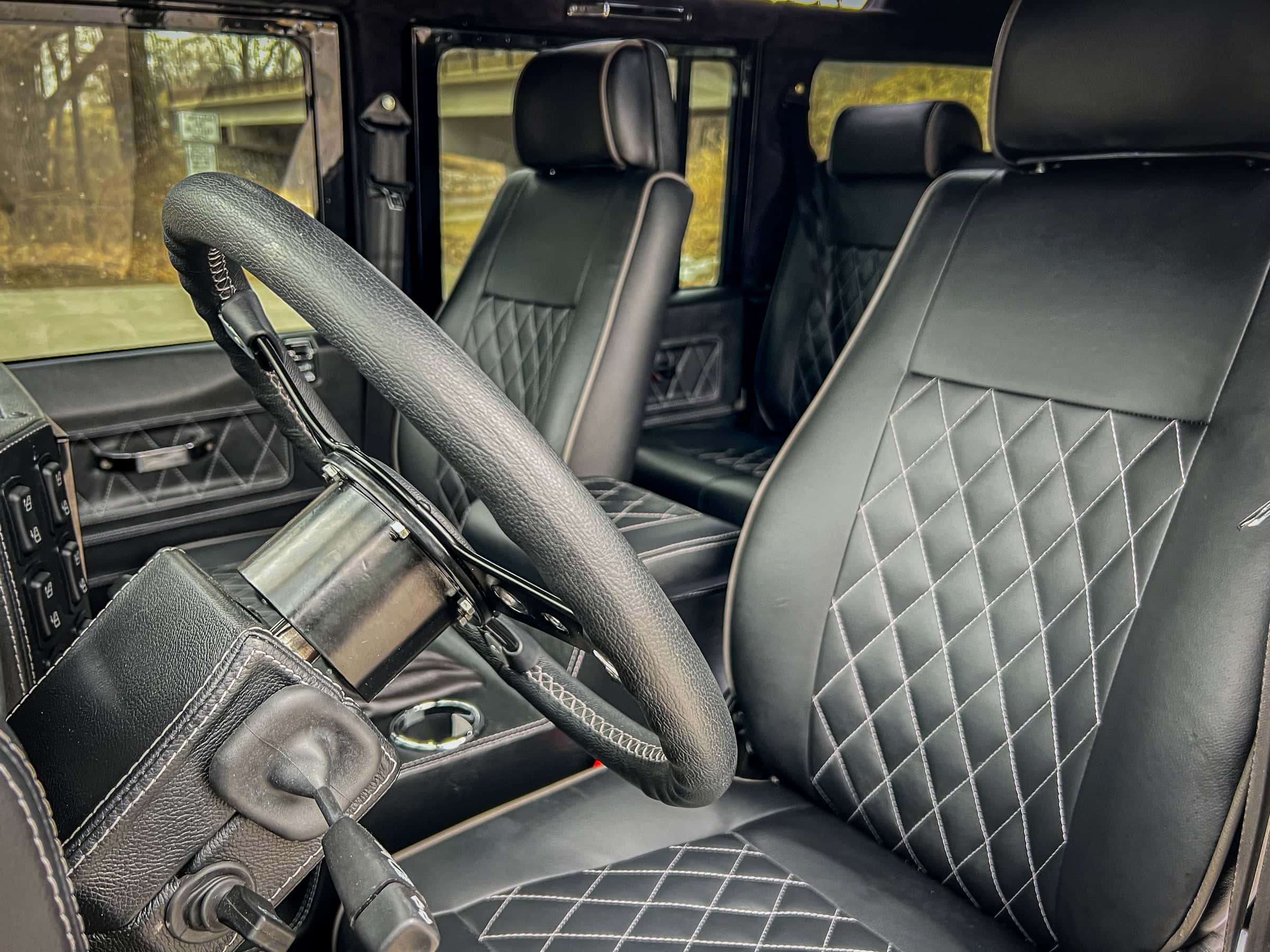 Interior view of a custom Land Rover Defender showcasing premium black leather seats with diamond stitching