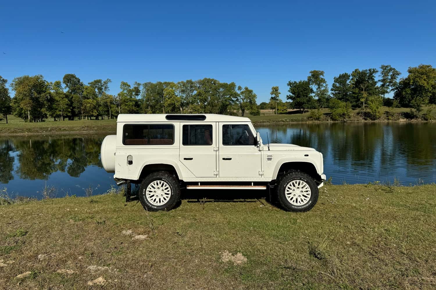 Custom Land Rover Defender parked by a serene lake
