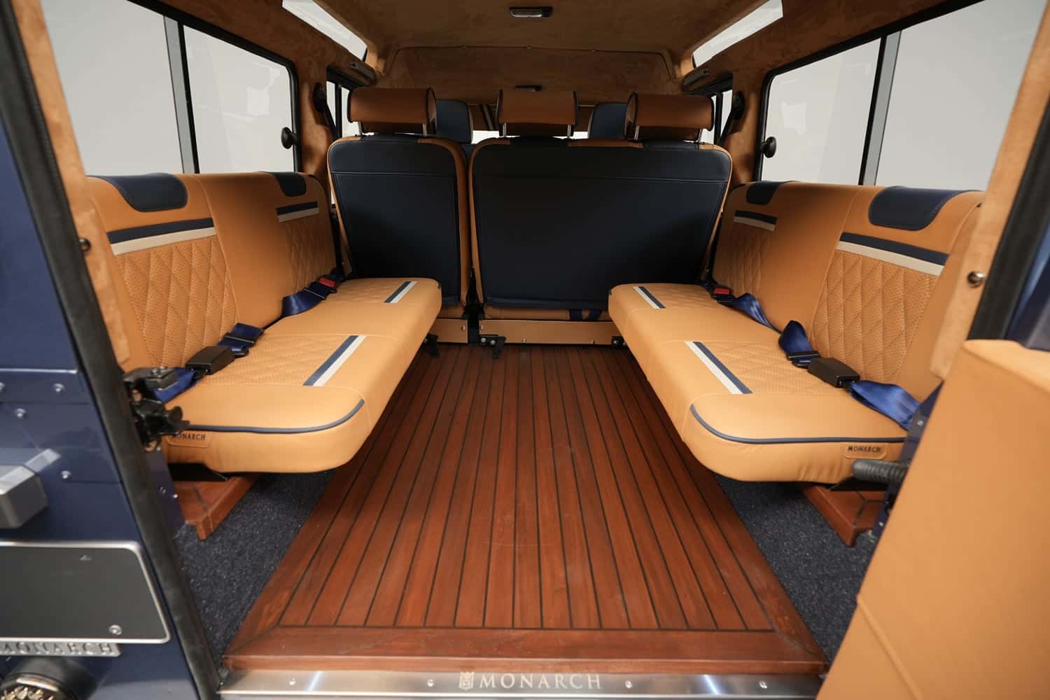 Interior view of a luxury custom Land Rover Defender showcasing spacious tan leather seating and wooden flooring