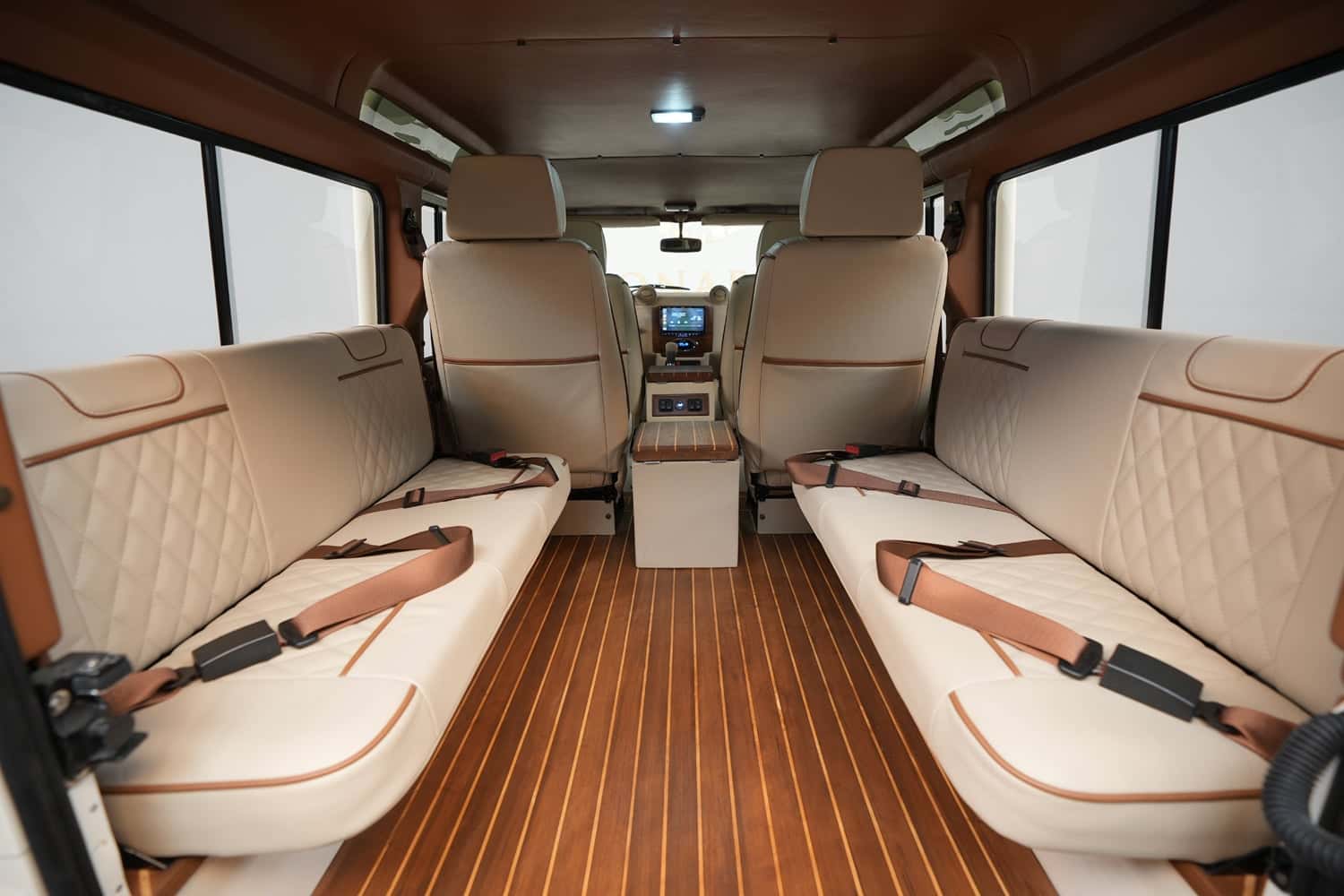 Interior view of a bespoke Land Rover Defender featuring tan leather seats and wooden flooring