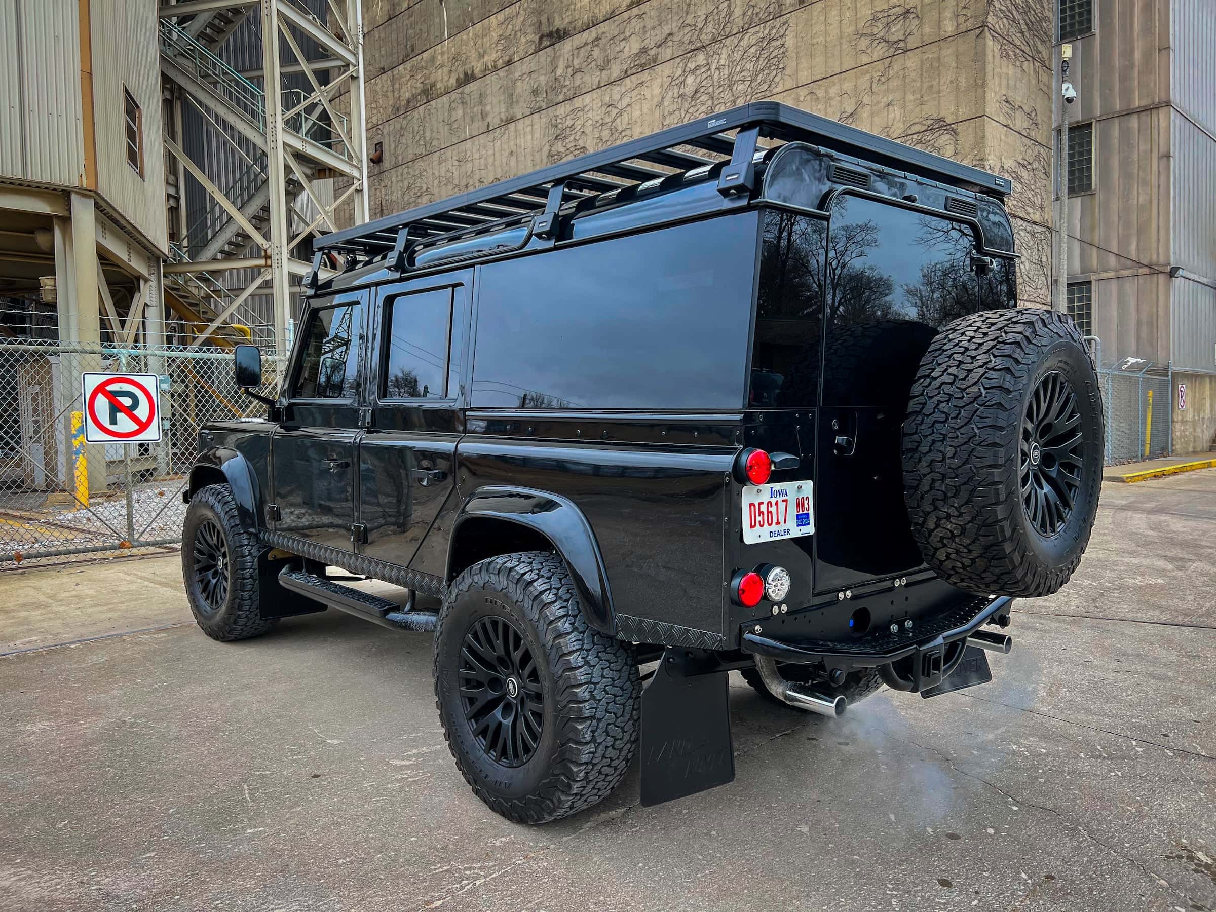 Black modified Land Rover Defender with off-road tires and roof rack