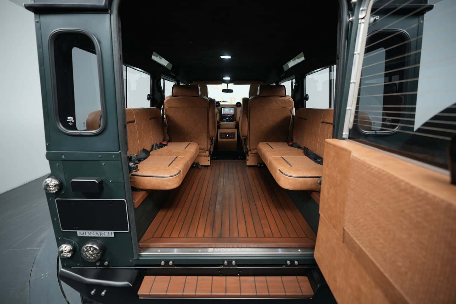 Interior view of a custom Land Rover Defender showing luxurious seating and wooden flooring