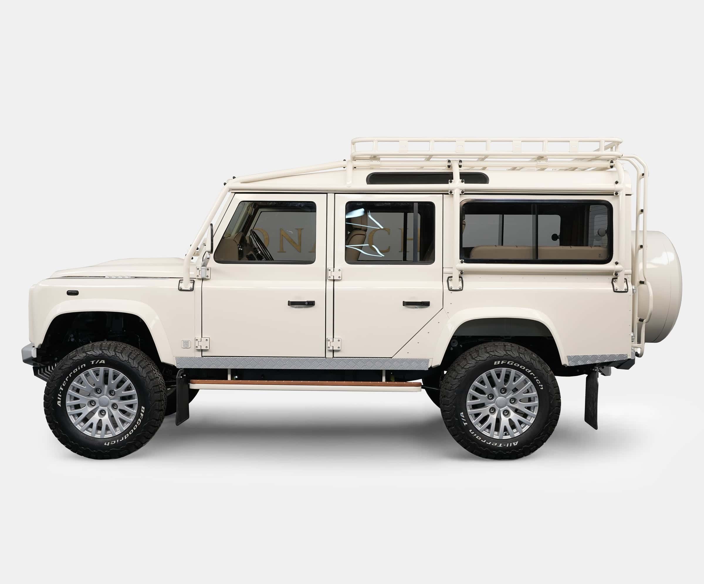 Side view of a bespoke Land Rover Defender in cream color with a roof rack and luxury wheels