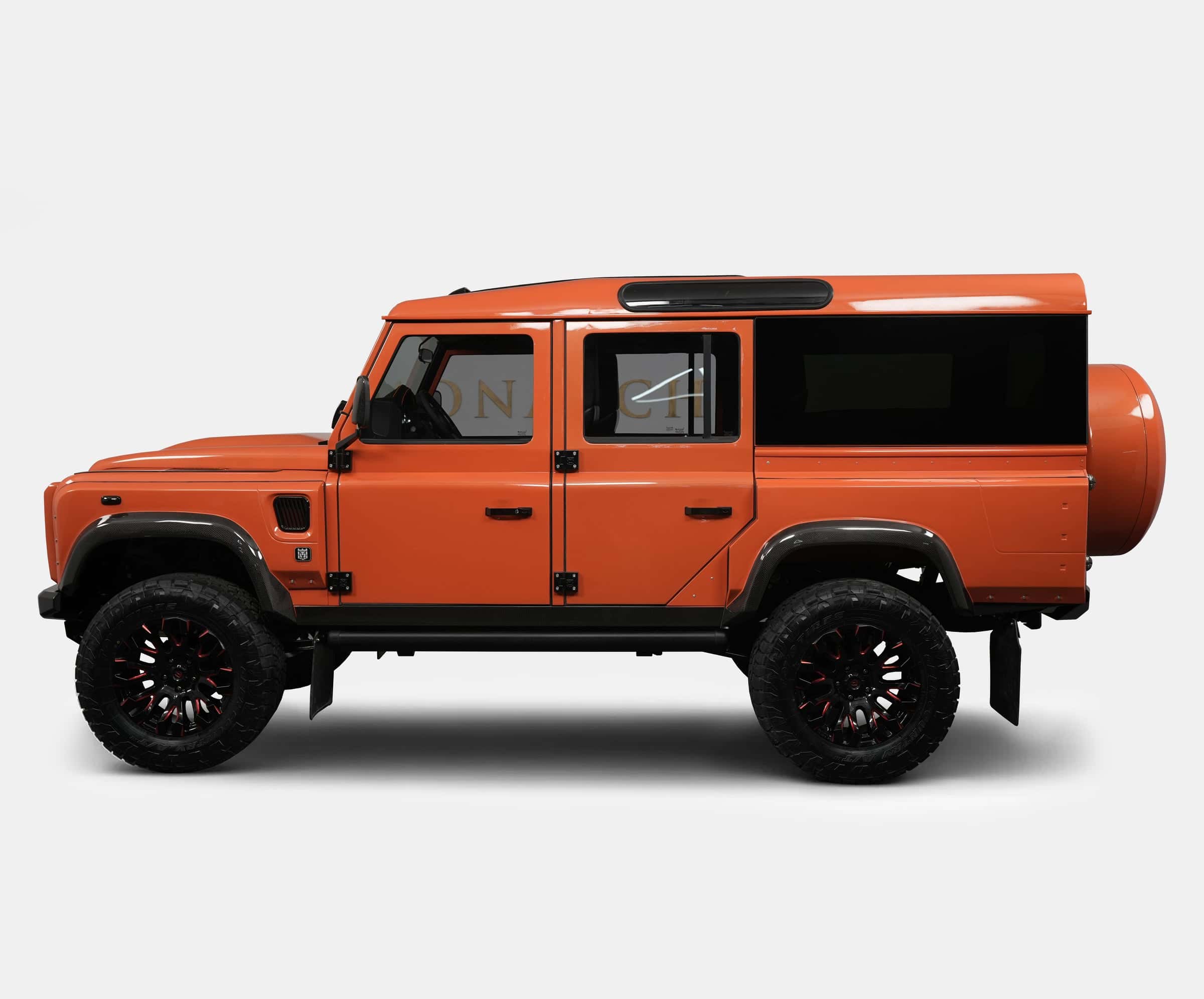 Custom orange Land Rover Defender with black accents and oversized wheels