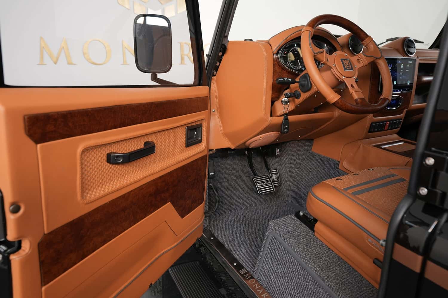 Close-up of a luxury Land Rover Defender interior featuring tan leather and wood accents