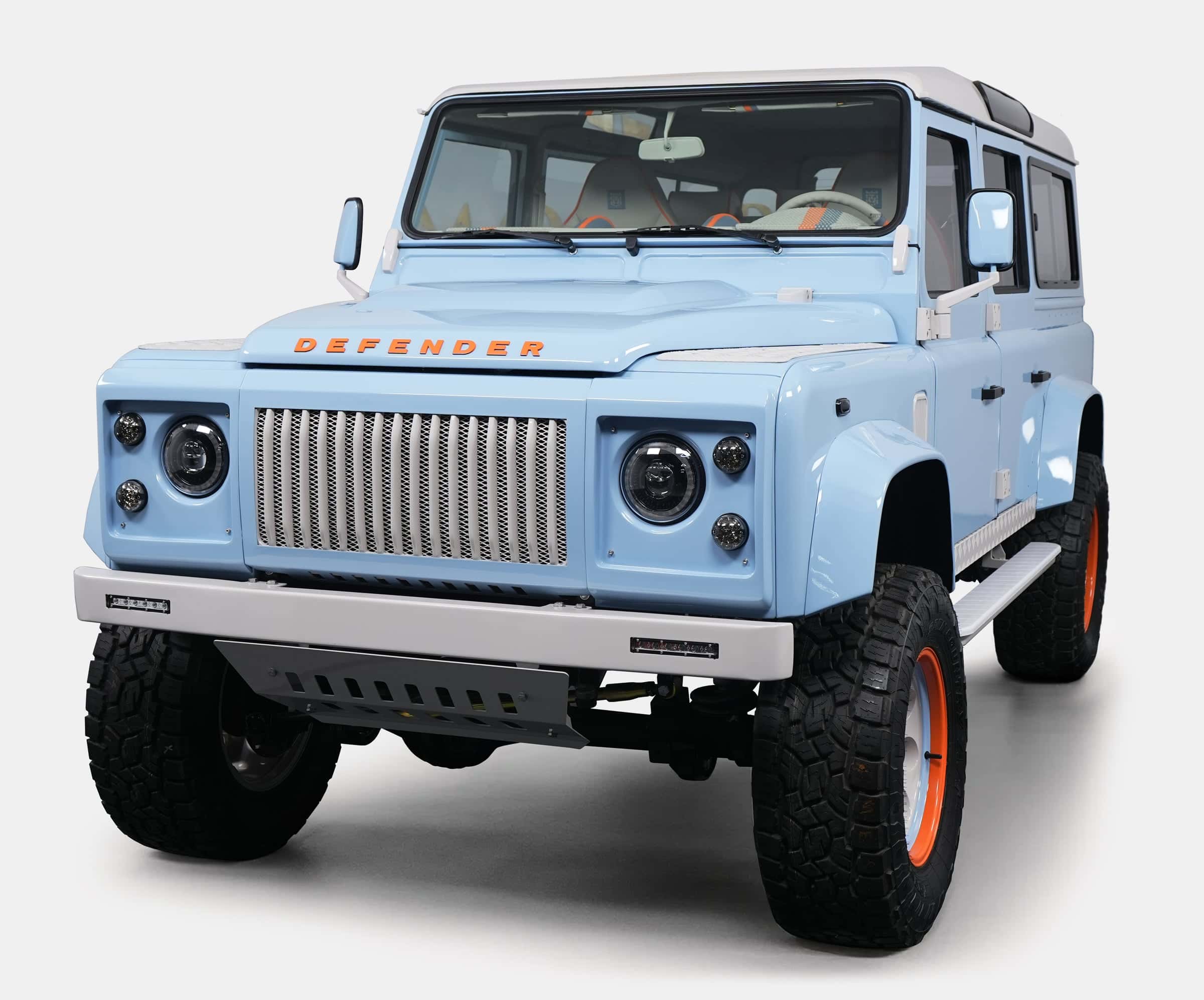 Custom Land Rover Defender in light blue with orange accents and rugged tires