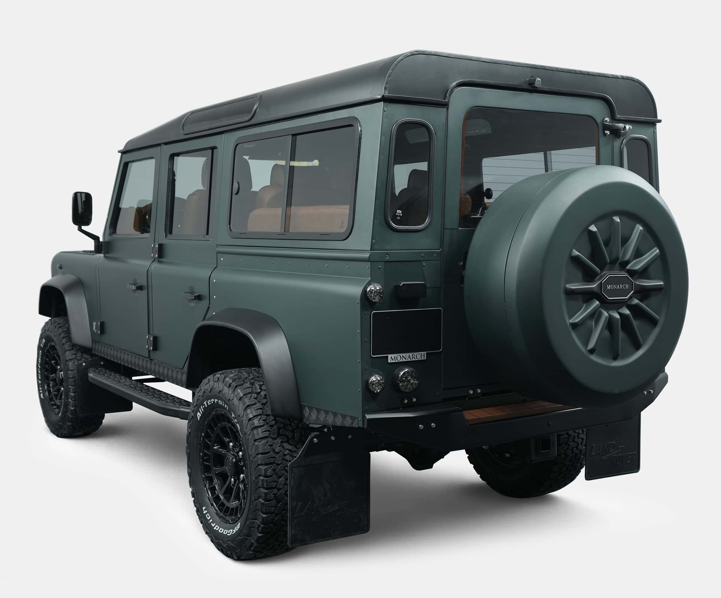 Rear view of a bespoke Land Rover Defender in matte green finish with custom wheels and spare tire