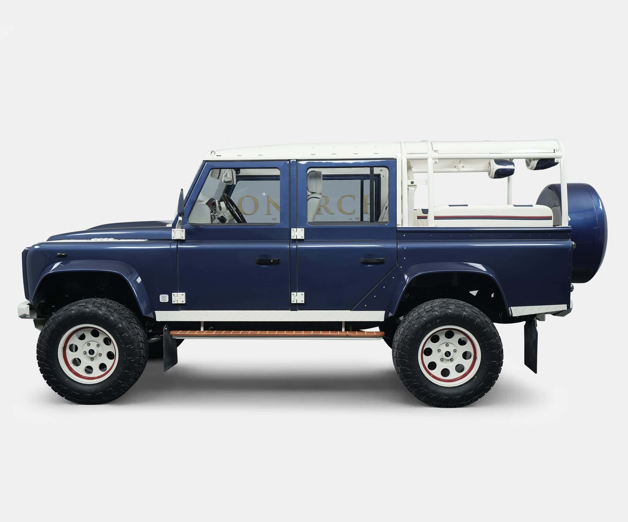 Side view of a custom blue Land Rover Defender with a unique design and off-road tires