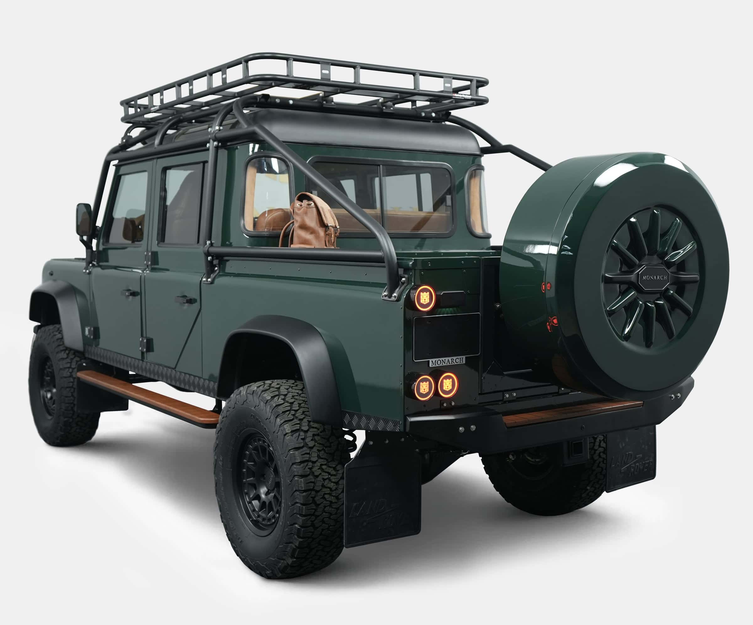 Rear view of a custom Land Rover Defender with a green finish and roof rack, showcasing luxury features