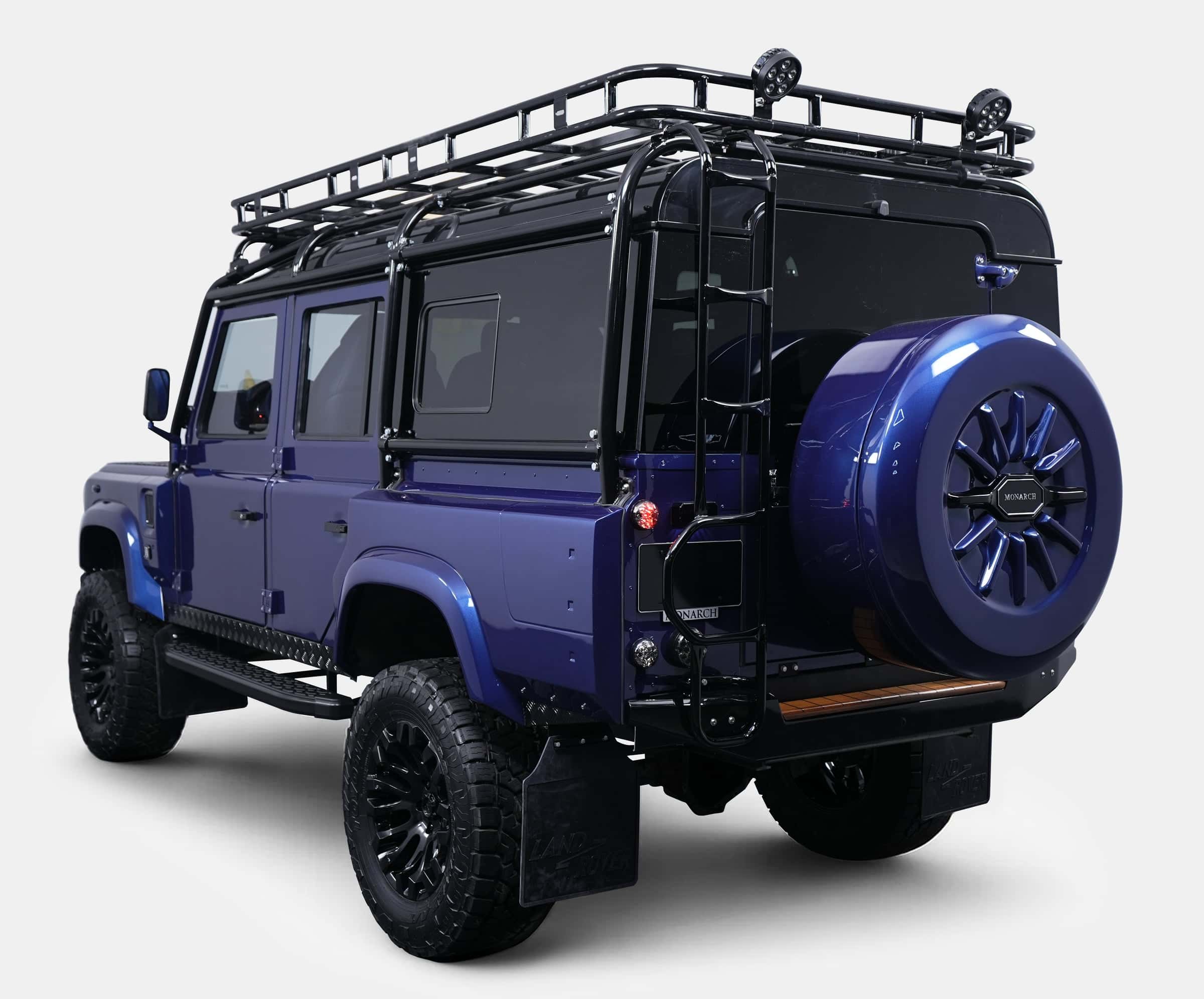 Rear view of a bespoke blue Land Rover Defender with a roof rack and custom wheels