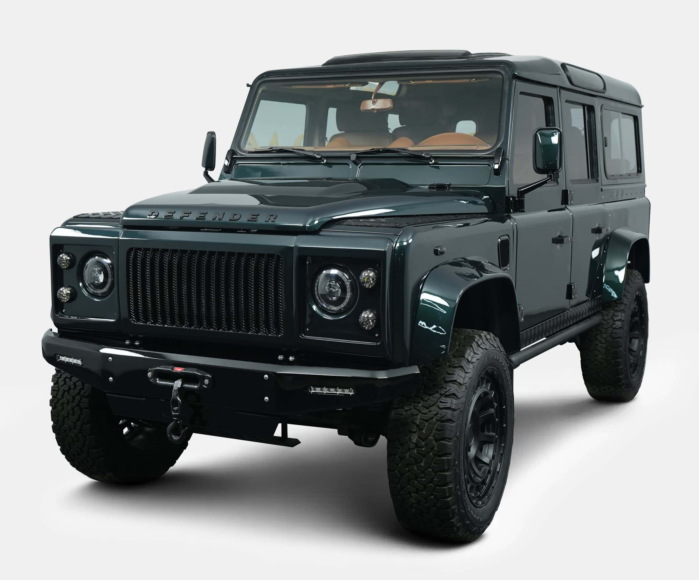 Bespoke Land Rover Defender in dark green with custom front grille and rugged tires